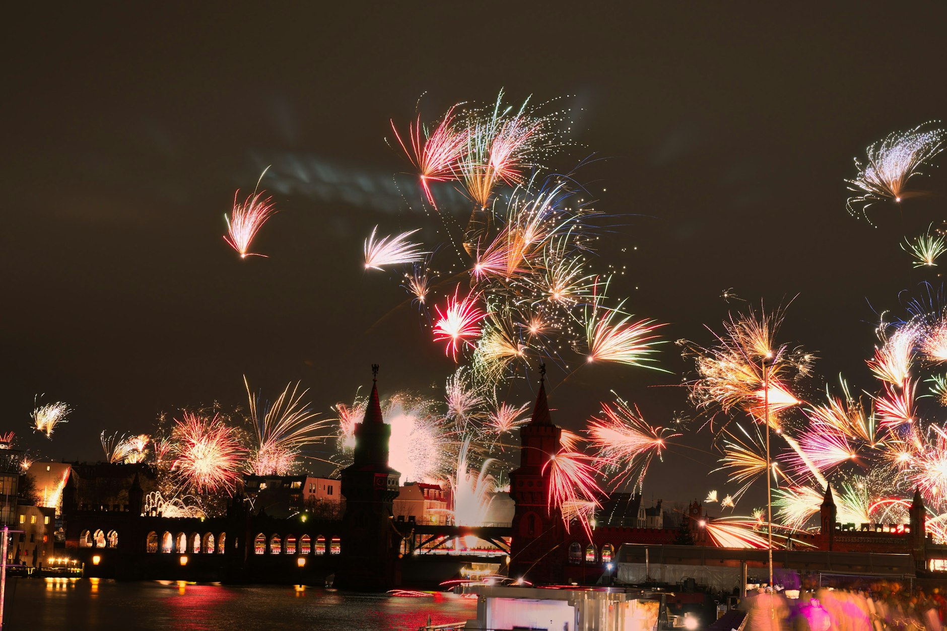 Feuerwerkskörper gehen an Silvester hinter der Oberbaumbrücke in den Nachthimmel hoch.