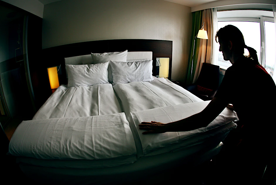 Eine Angestellte macht in einem Hotel das Bett. 