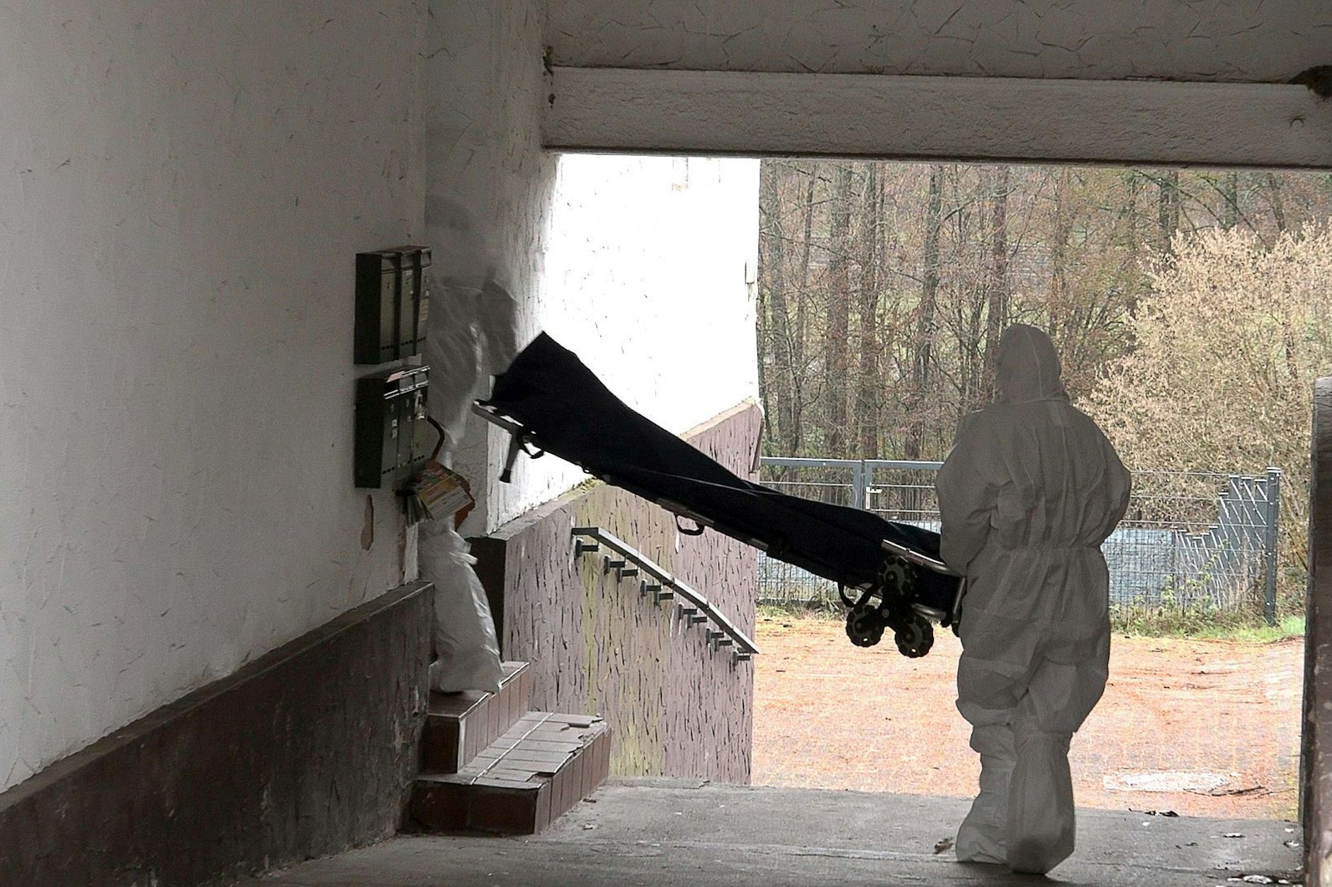 Beamte der Spurensicherung bringen eine Trage in ein Wohnhaus.