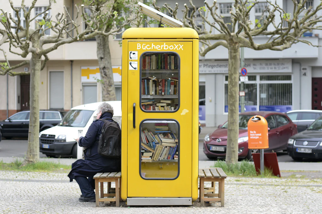 Ein Mann liest vor einer Bücherbox.