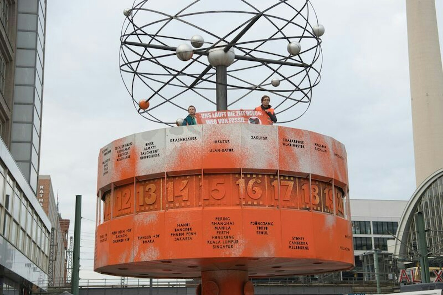 Nach dem Farbanschlag schauen Aktivisten der Letzten Generation vin der beschmierten Weltzeituhr.