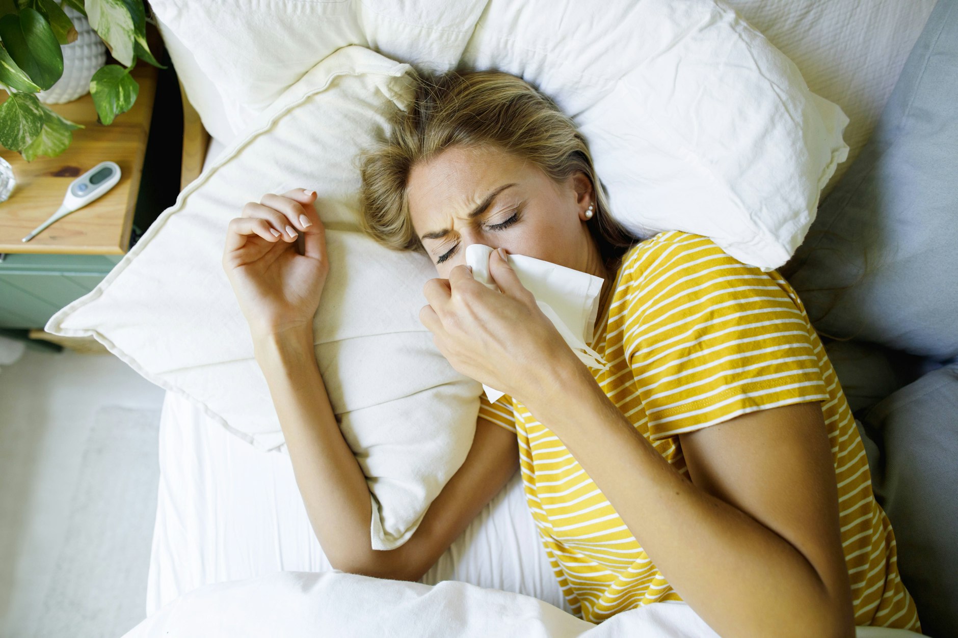 Eine Influenza-Patientin liegt mit Grippesymptomen im Bett.