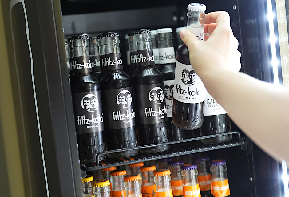 Eine Mitarbeiterin greift nach einer Flasche Fritz-Kola in einem Kühlschrank in der Firmenzentrale der Fritz-Kola GmbH.