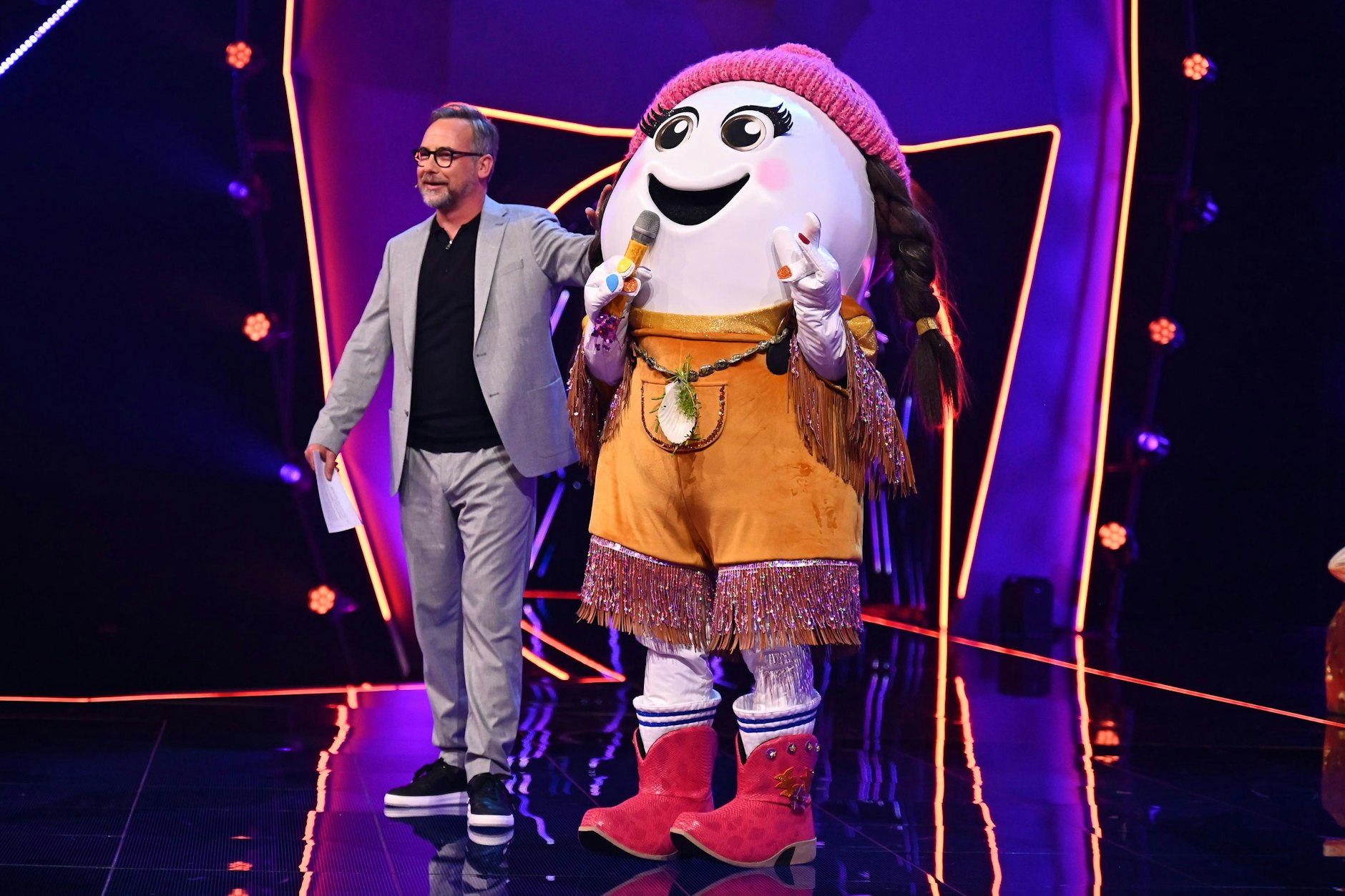 Eggi und Matthias Opdenhövel auf der Bühne von Masked Singer. Viele Zuschauer glauben, dass Evelyn Burdecki oder Collien Fernandes im Kostüm stecken.