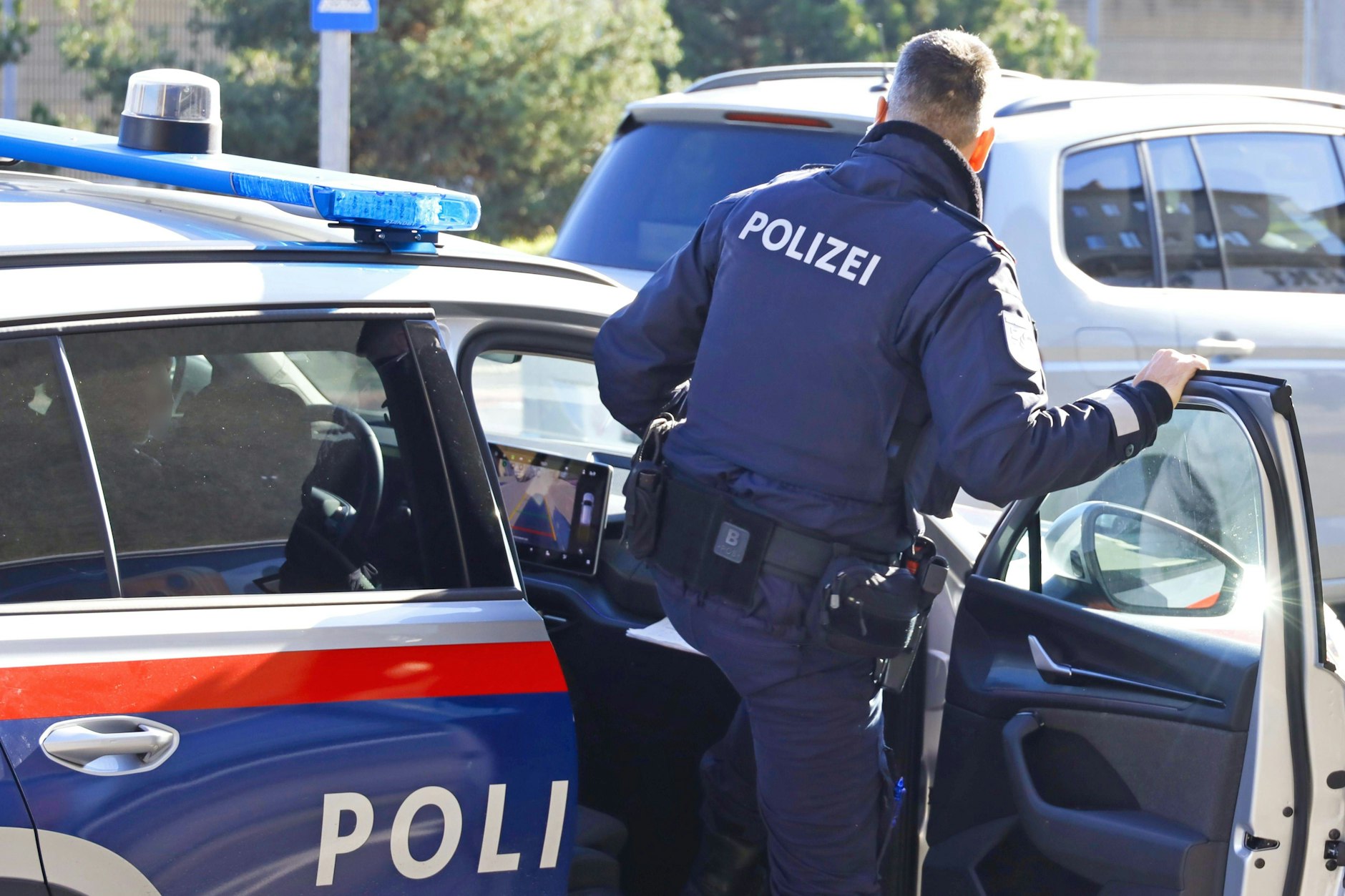 Ein österreichischer Polizist steigt in ein Polizeiauto (Symbolbild).
