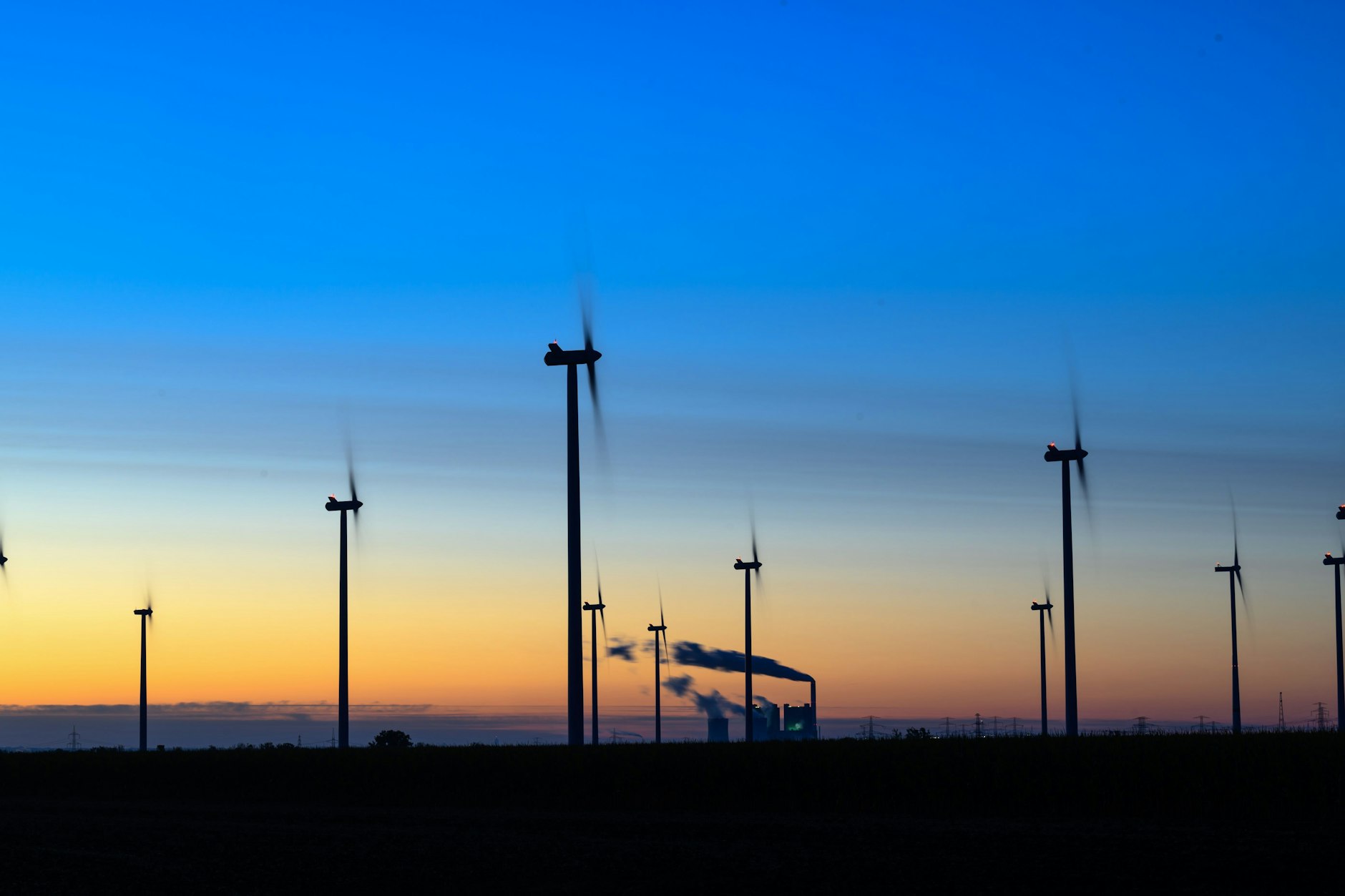 Windräder drehen sich vor der Kulisse des Braunkohlekraftwerks Schkopau, Sachsen-Anhalt.