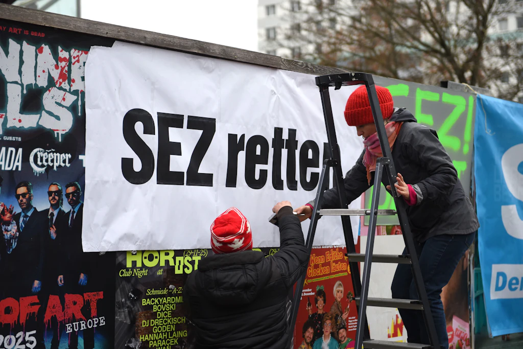 Mitglieder einer Bürgerinitiative haben bringen ein Plakat „SEZ retten“ vor dem Abrissgebäude an.