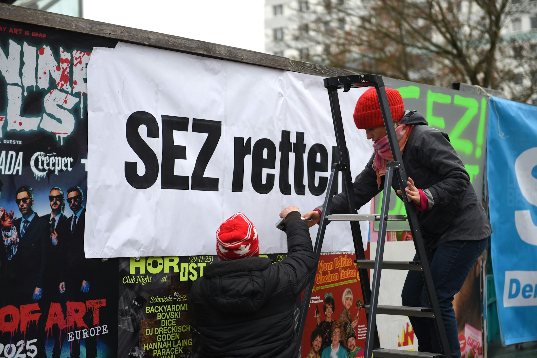 Mitglieder einer Bürgerinitiative haben bringen ein Plakat „SEZ retten“ vor dem Abrissgebäude an.