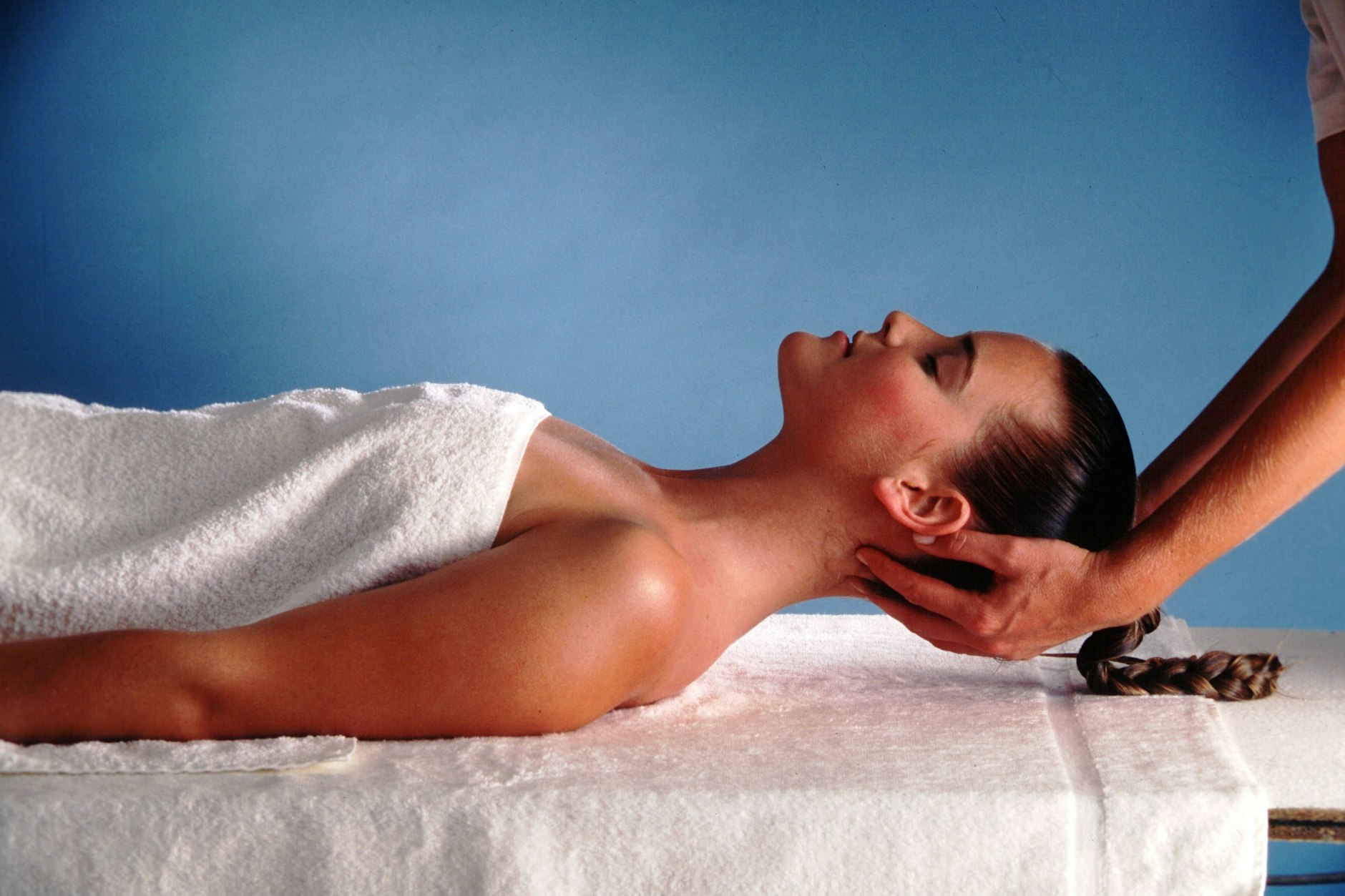 Eine junge Frau entspannt sich bei einer Ayurveda-Kopfmassage.