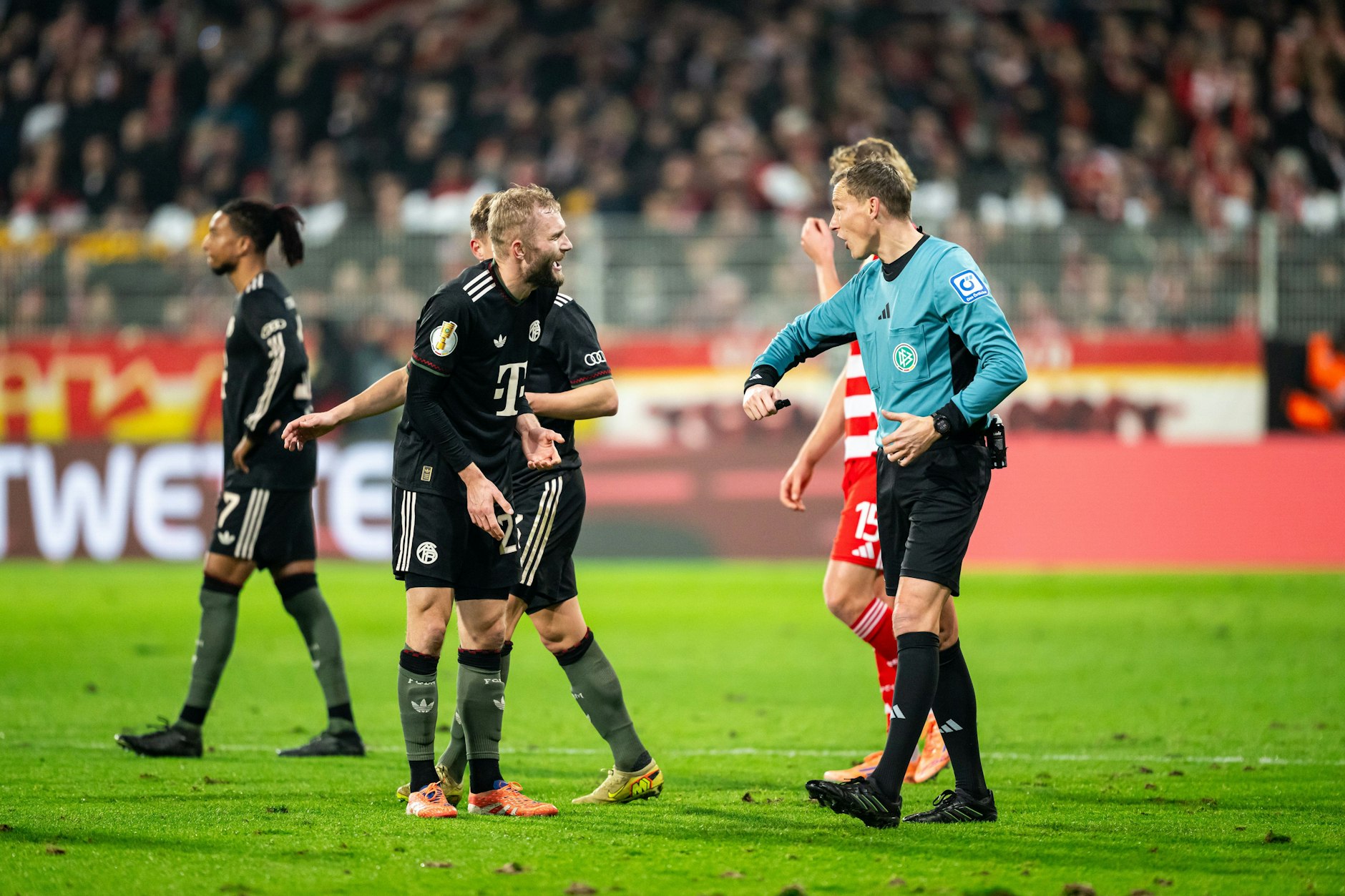 Schiedsrichter Martin Petersen (r.) erklärt Bayern Münchens Konrad Laimer seinen Elfmeterpfiff für den 1. FC Union Berlin zu Beginn der zweiten Hälfte.