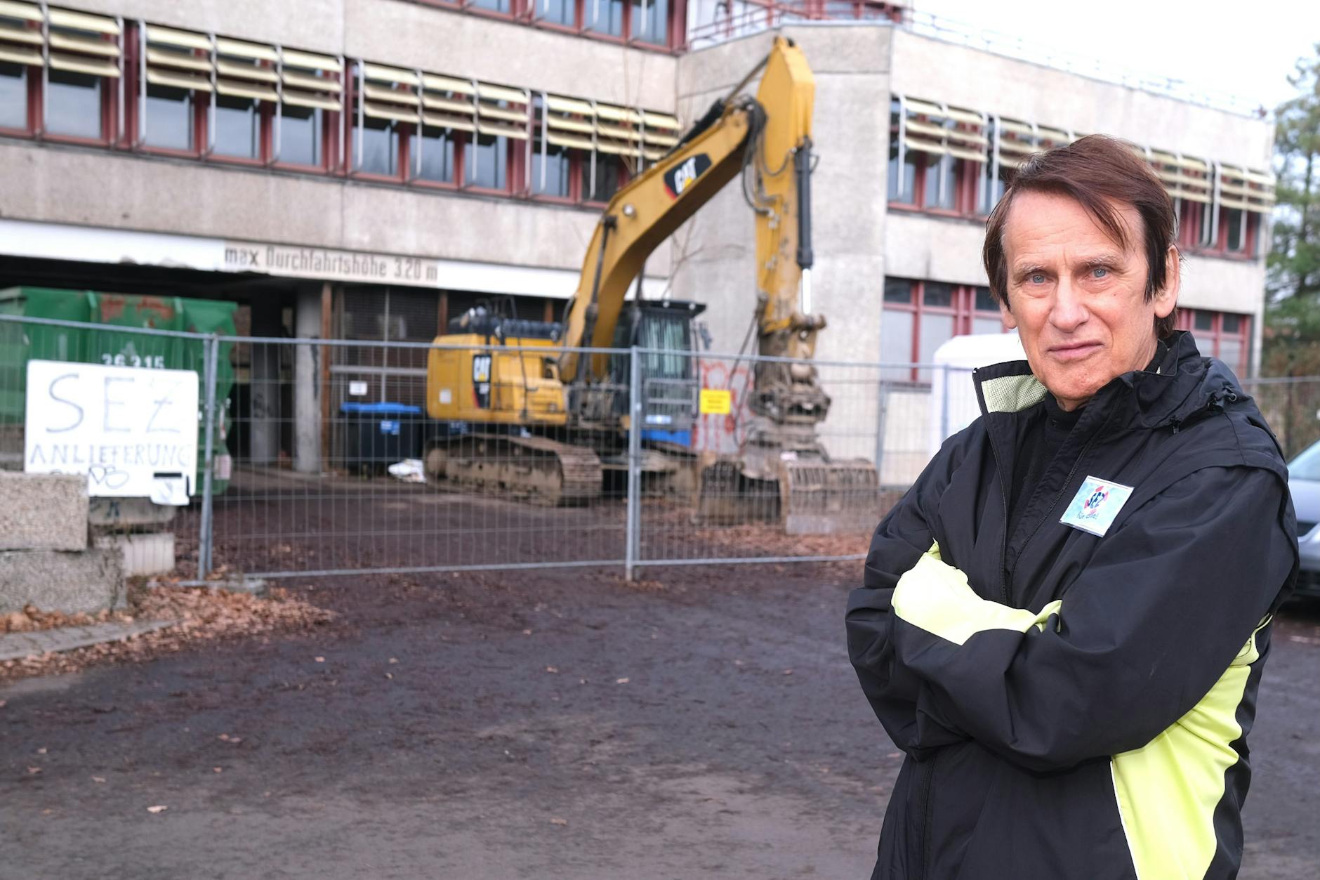 „Medizin nach Noten“-Moderator Karl Heinz Wendorff vor dem Abriss-Bagger, der bereits an der Fassade des SEZ wütete.