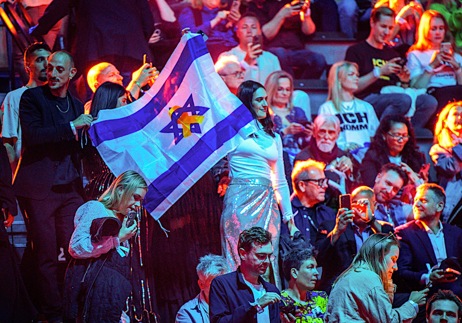 Mai 2025: Musikfans der Teilnehmerin aus Israel stehen mit der israelischen Fahne vor dem zweiten Halbfinale des 69. Eurovision Song Contests in der St. Jakobshalle.