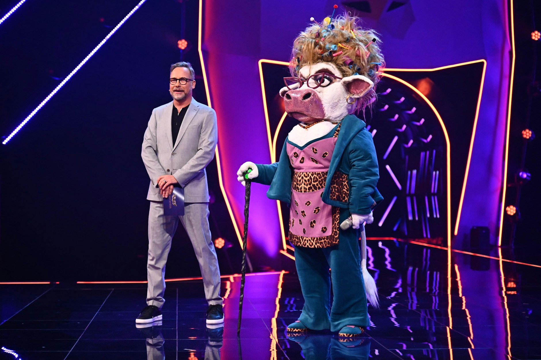 Kuh Muuhnika auf der Bühne von Masked Singer, zusammen mit dem Moderator Matthias Opdenhövel. Er gehört zu den wenigen Personen, die die Identitäten der Stars kennen.