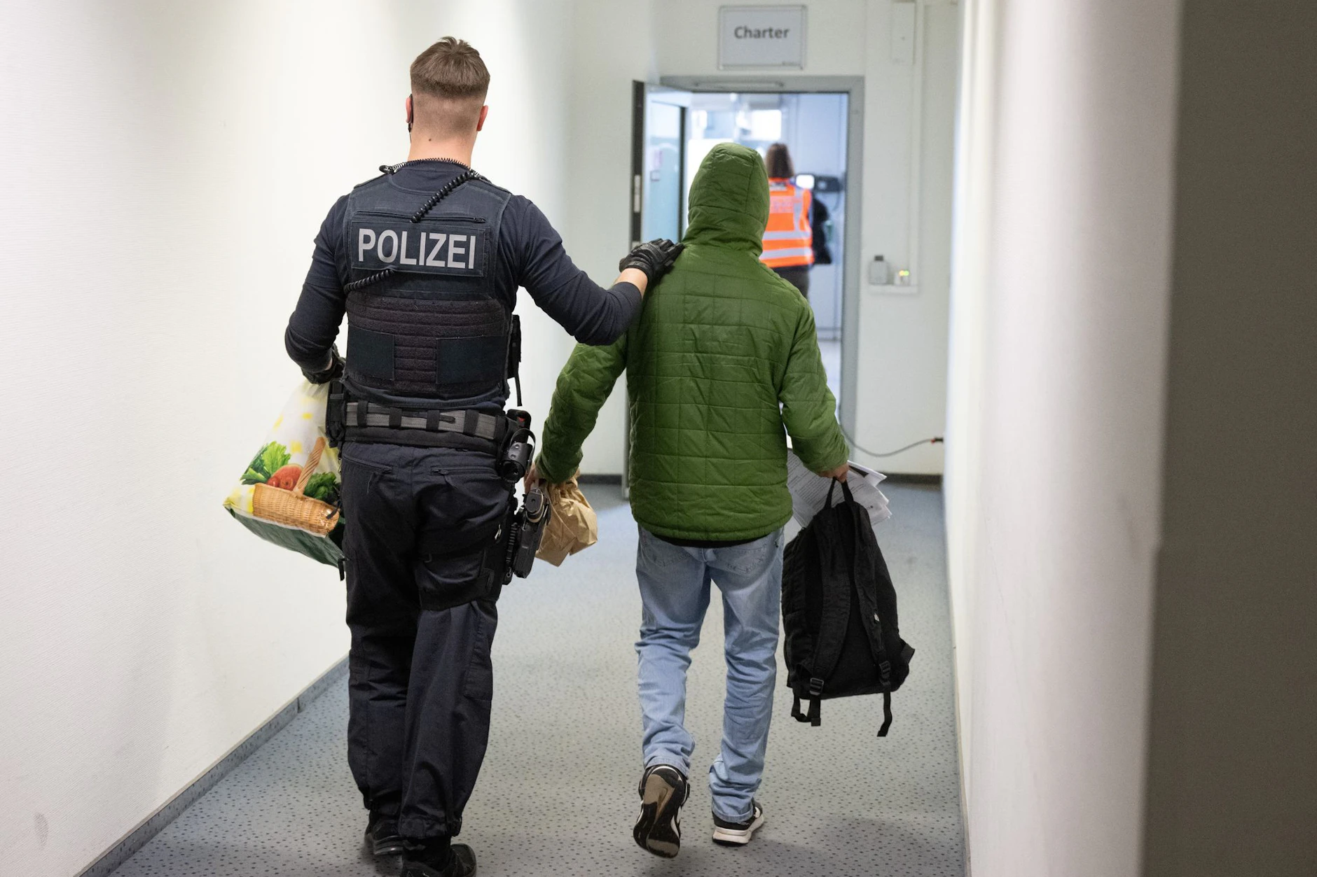 Ein Polizeibeamter bringt einen Mann zu einem Abschiebeflug nach Pakistan.