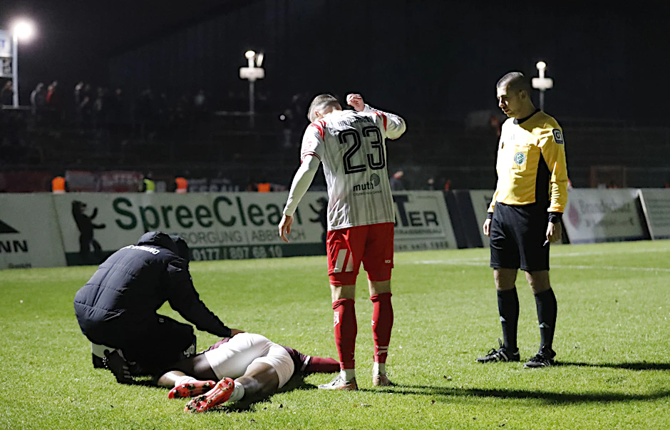 Americo Neves liegt mit Schmerzen am Boden, BFC-Physio Elias Ulsamer ist als erster Helfer beim Dynamo-Pechvogel.