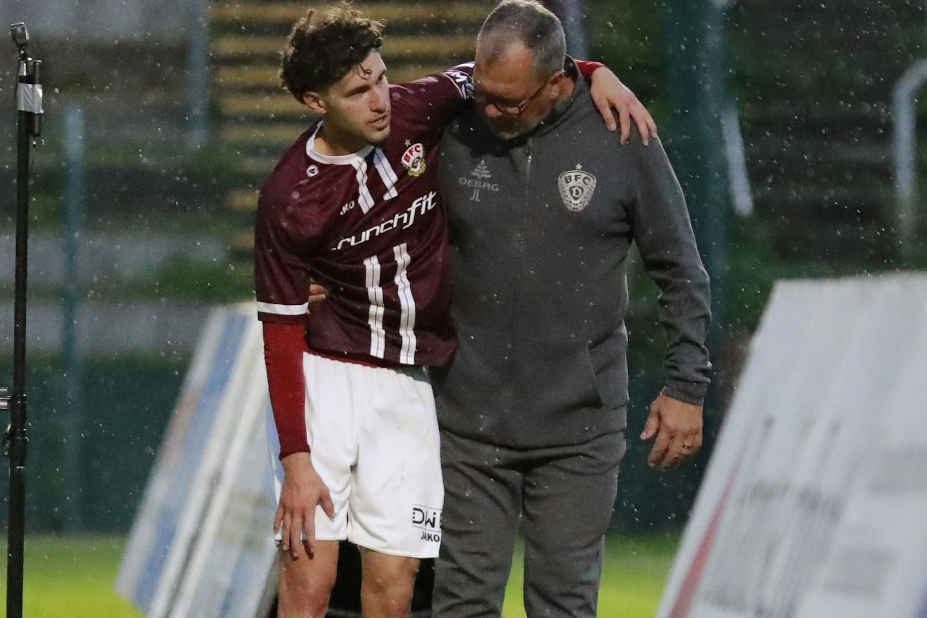 Can Karatas erwischte es gegen den Greifswalder FC. Auf BFC-Teammanager Jörn Lenz gestützt zeigt er, wo die Schmerzen sind.