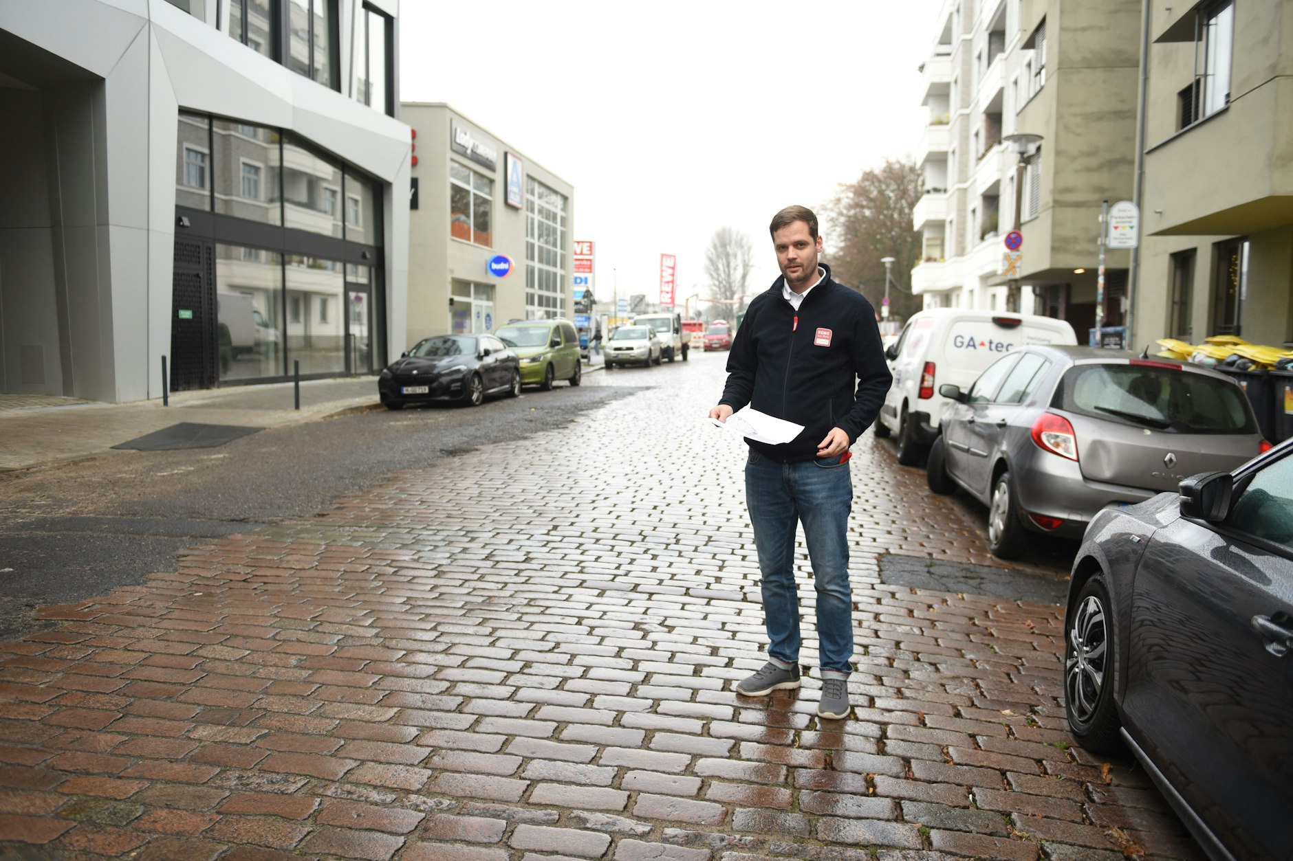 Rewe-Filialleiter Dennis Henkelmann zeigt, an welcher Stelle in der Revaler Straße die Poller installiert werden.