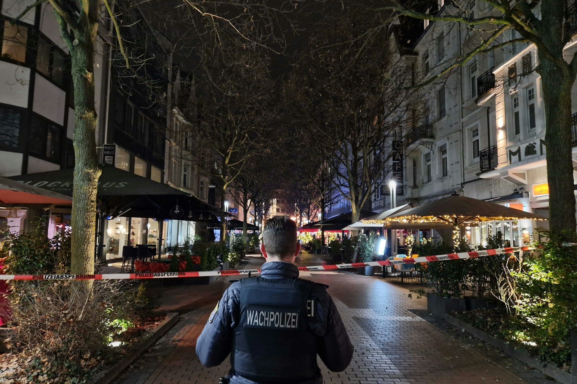 Ein Mitarbeiter der Wachpolizei steht an einem Absperrband in der Innenstadt von Gießen.  