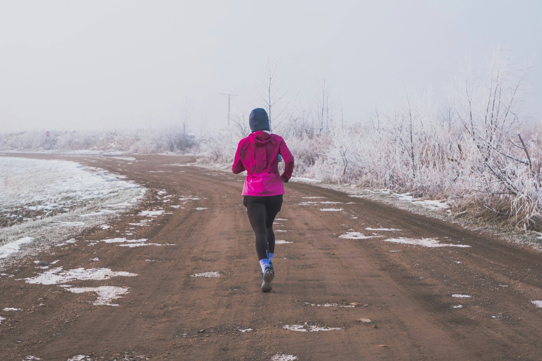 Frau joggt im Winter allein auf einem Schotterweg