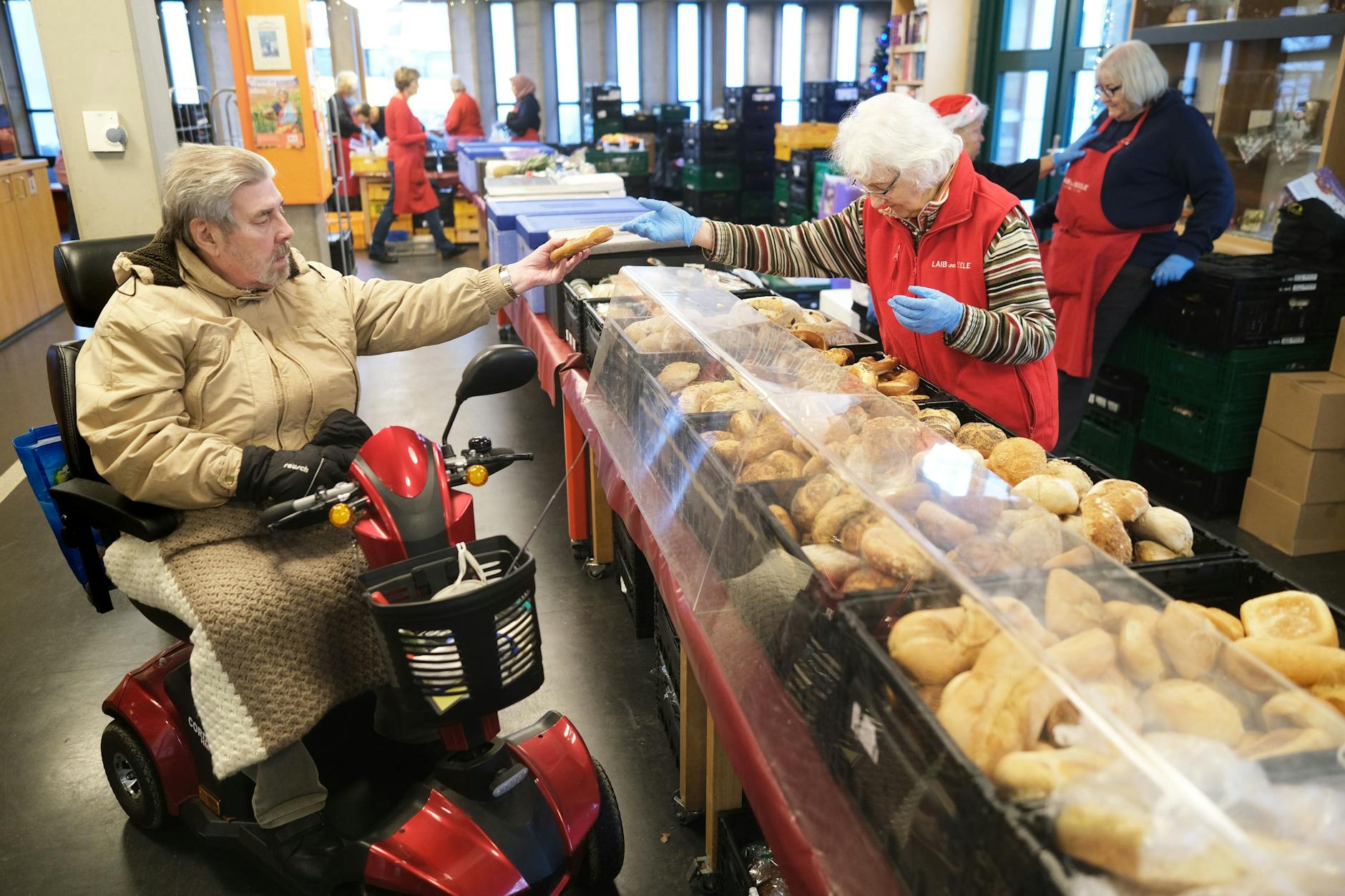 Rollstuhlfahrer Winne Viehmann gehört zu den Menschen, die bei der Berliner Tafel auf Hilfe angewiesen sind. Hier wird er von Helferin Gerda Dellbrügge bedient.