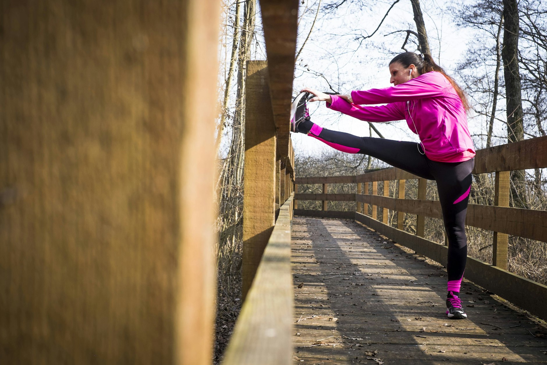 Eine Frau macht Stretchingübungen auf einer Brücke.