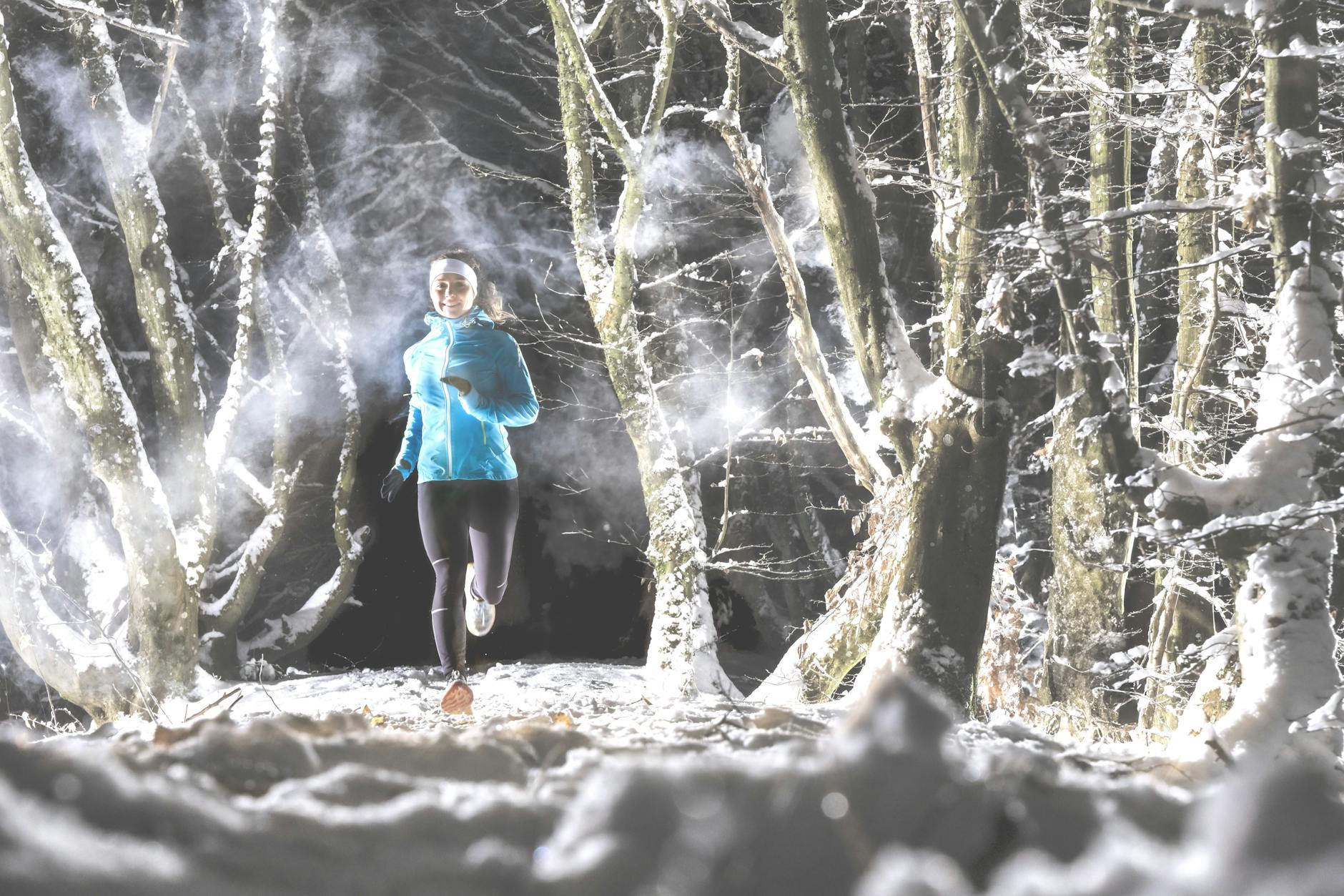 Eine Läuferin joggt glücklich durch den Wald.