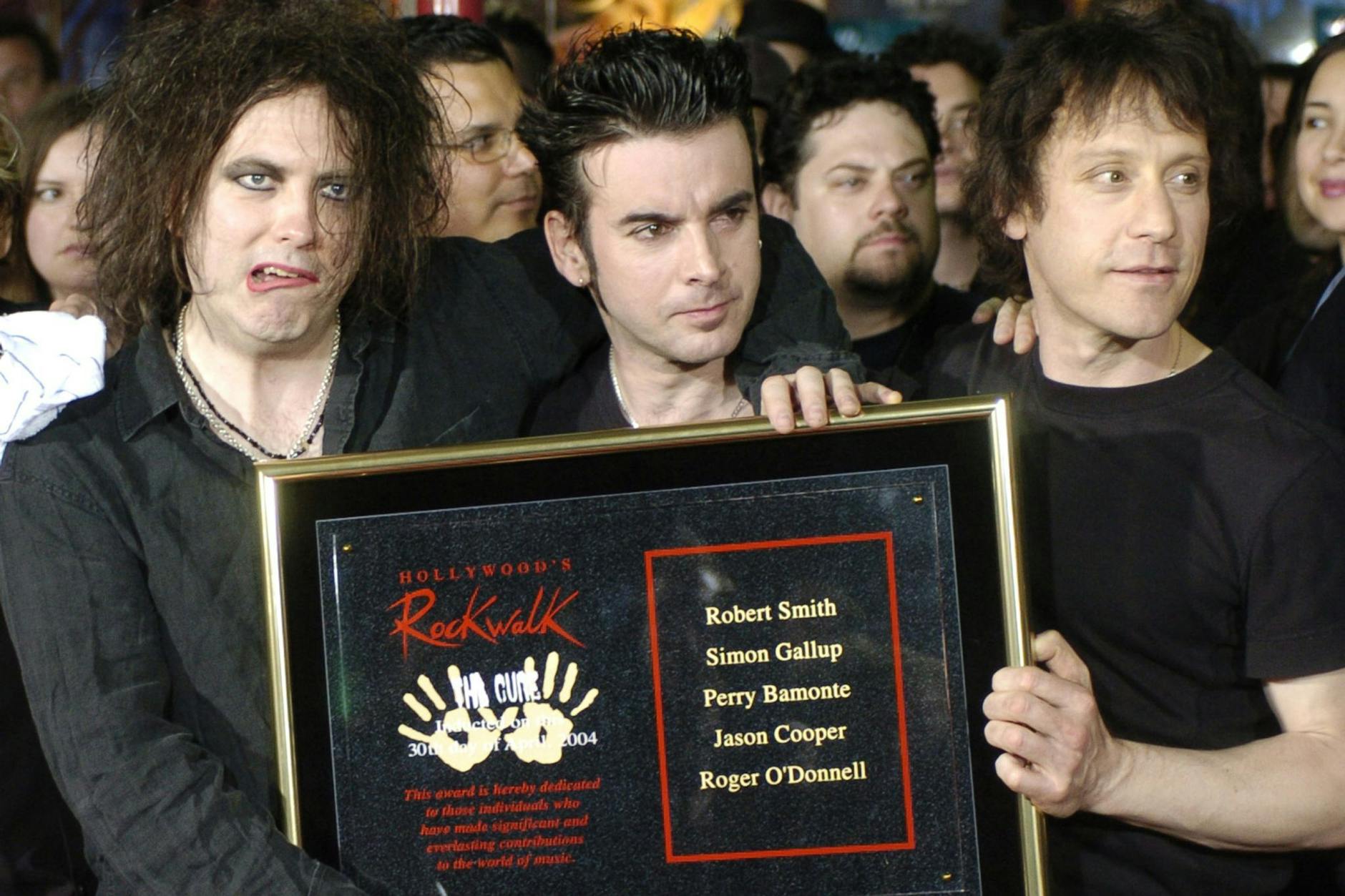 Robert Smith (von Links) Simon Gallup und Perry Bamonte von der britischen Rockgruppe The Cure halten im April 2004 eine Plakette, nachdem sie in den Hollywood Rockwalk aufgenommen wurden.