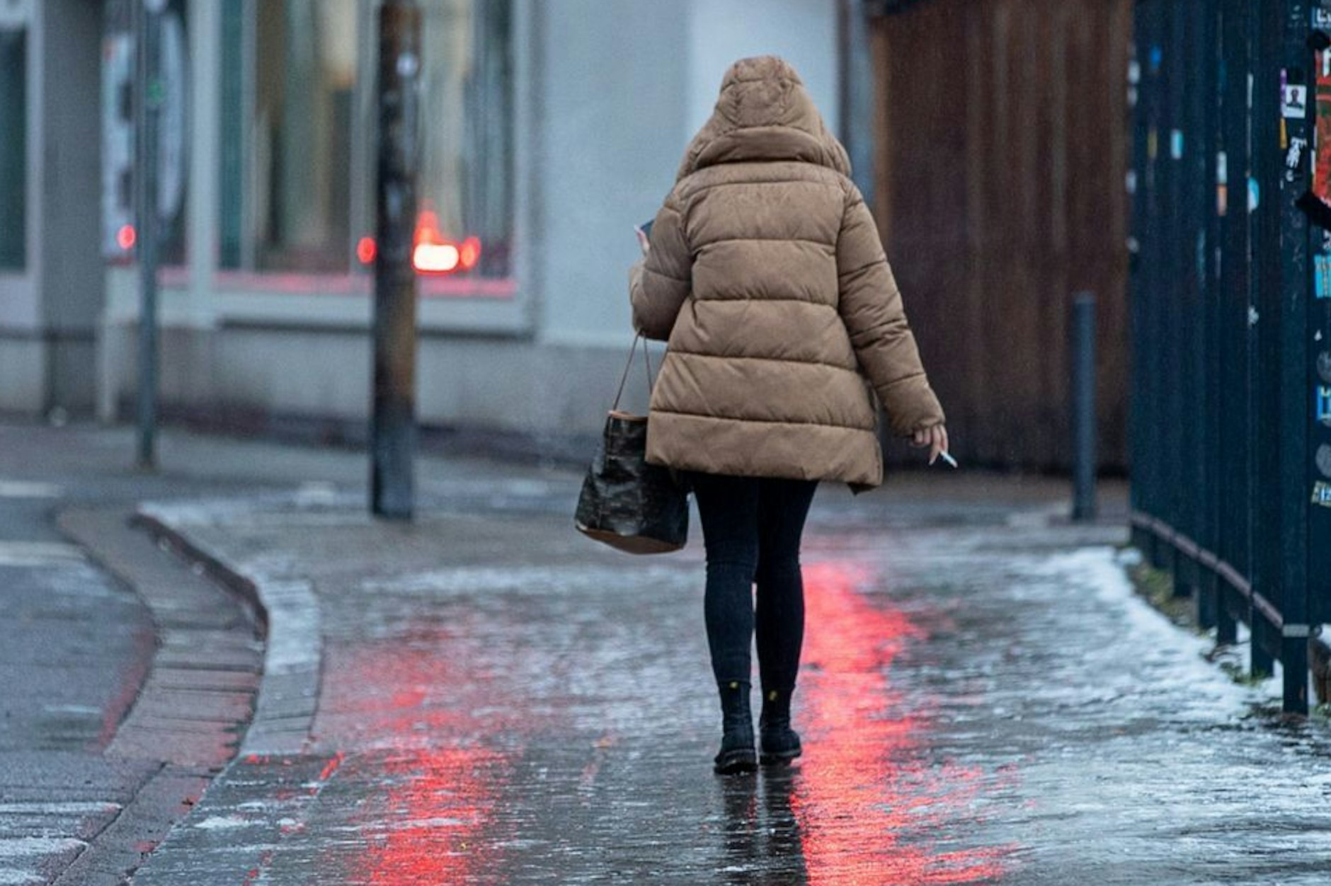 Spiegelglatte Gehwege in der Stadt. Eine Fußgängerin kämpft sich vorsichtig über vereiste Bürgersteige. Experten warnen vor anhaltender Glätte bis mindestens Neujahr.