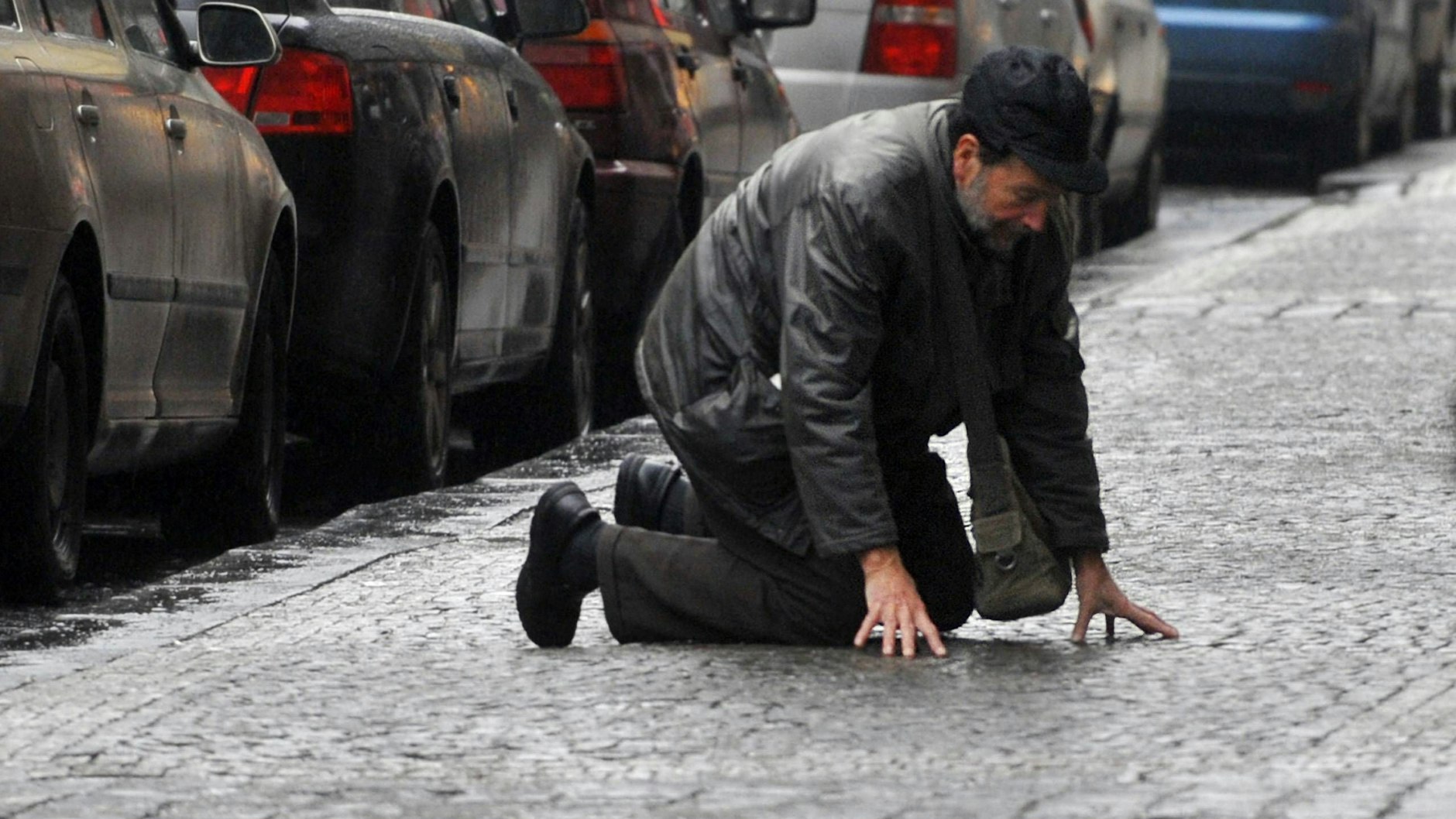 Ein Mann ist auf einem vereisten Gehweg ausgerutscht und stützt sich mit den Händen ab. Bei der aktuellen Glätte in Berlin und Brandenburg kommt es vermehrt zu Stürzen. (Symbolbild)