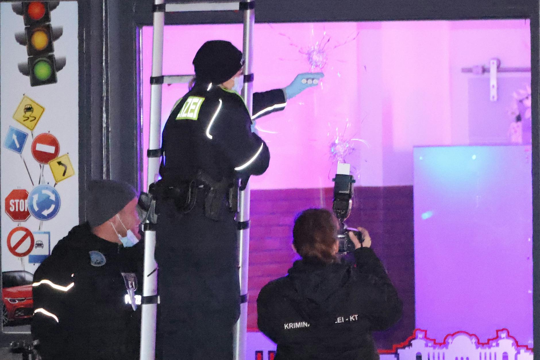 Schutzgelderpressung: Polizisten sichern für die Ermittlungen die Einschusslöcher im Schaufenster einer Fahrschule.