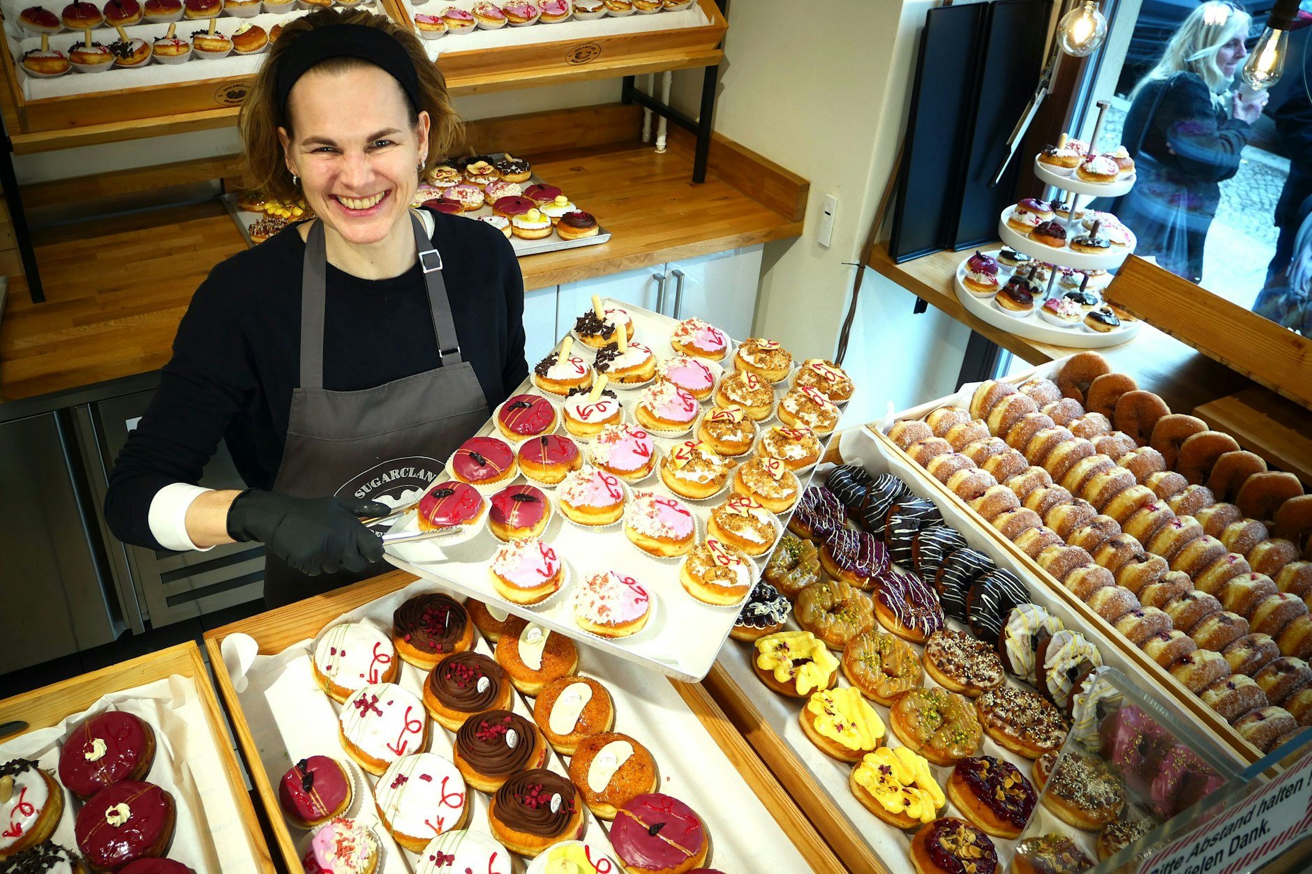 Pfannkuchen-Klassiker und bunte Donut-Varianten: Geschäftsführerin Britta Sarnes präsentiert Silvester-Gebäck in der Pfannkuchenmanufaktur Sugarclan in Berlin-Friedrichshain.