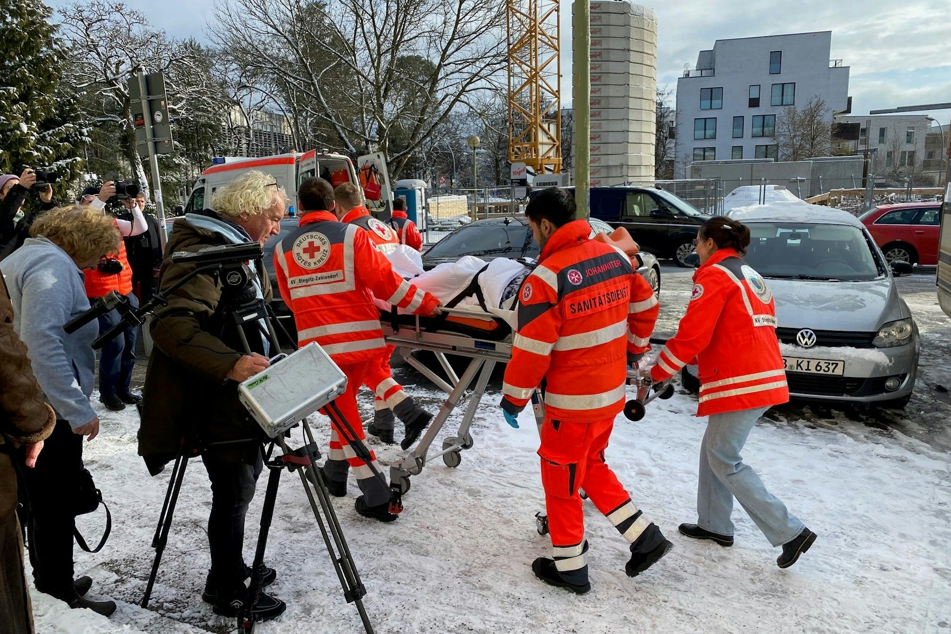 Während Kai Wegner vor die Presse tritt, wird ein Patient von Helfern des Deutschen Roten Kreuzes ins Krankenhaus gebracht.