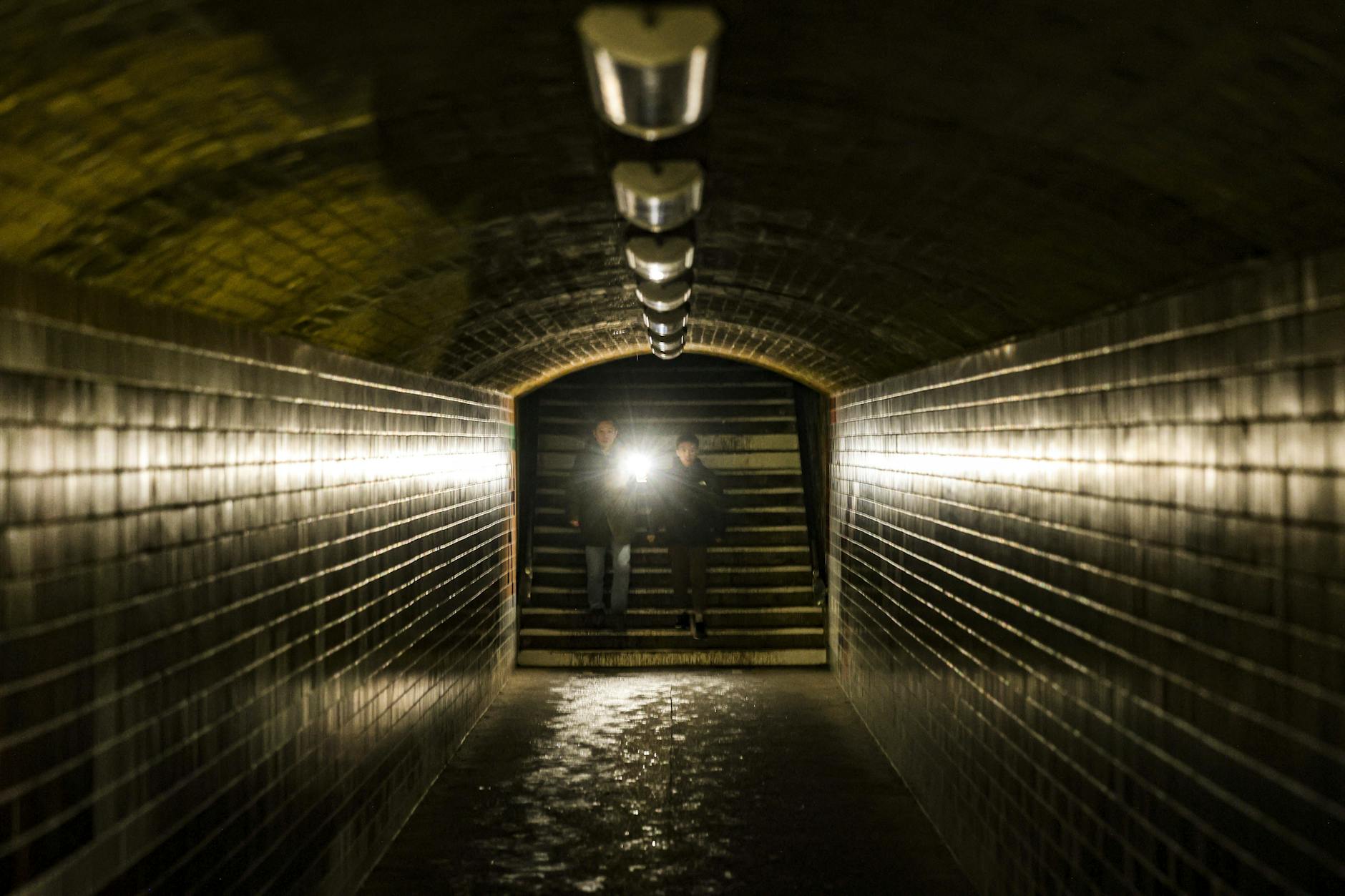 Menschen mit Taschenlampen in einer S-Bahn-Unterführung im Berliner Südwesten.