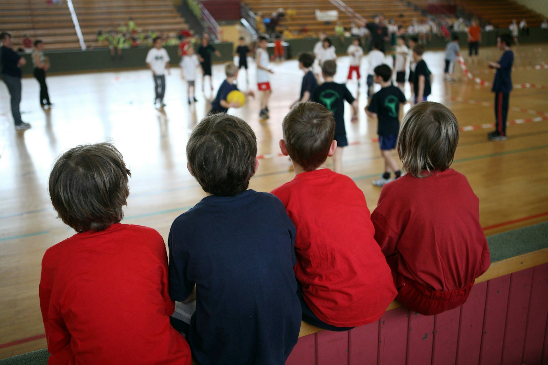 Kinder schauen beim Völkerballspiel in einer Turnhalle in Berlin zu.