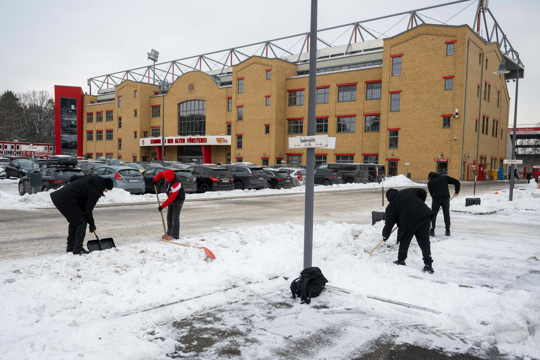 Fans und Angestellte befreien Wege und Parkplätze am Stadion von Schnee und Eis.