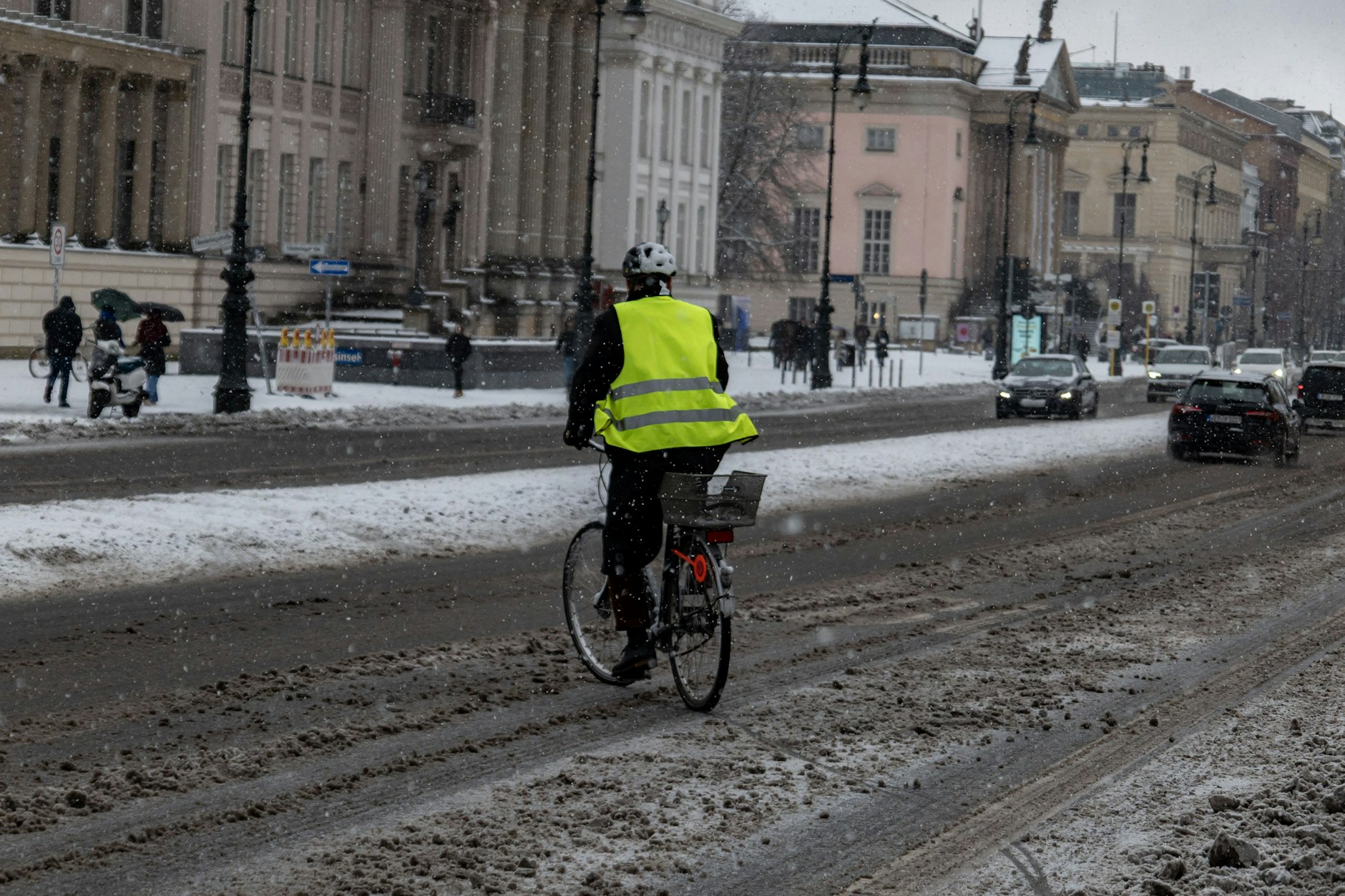 Ein Mann bahnt sich mit einem Fahrrad Unter den Linden den Weg durch Schnee und Eis.