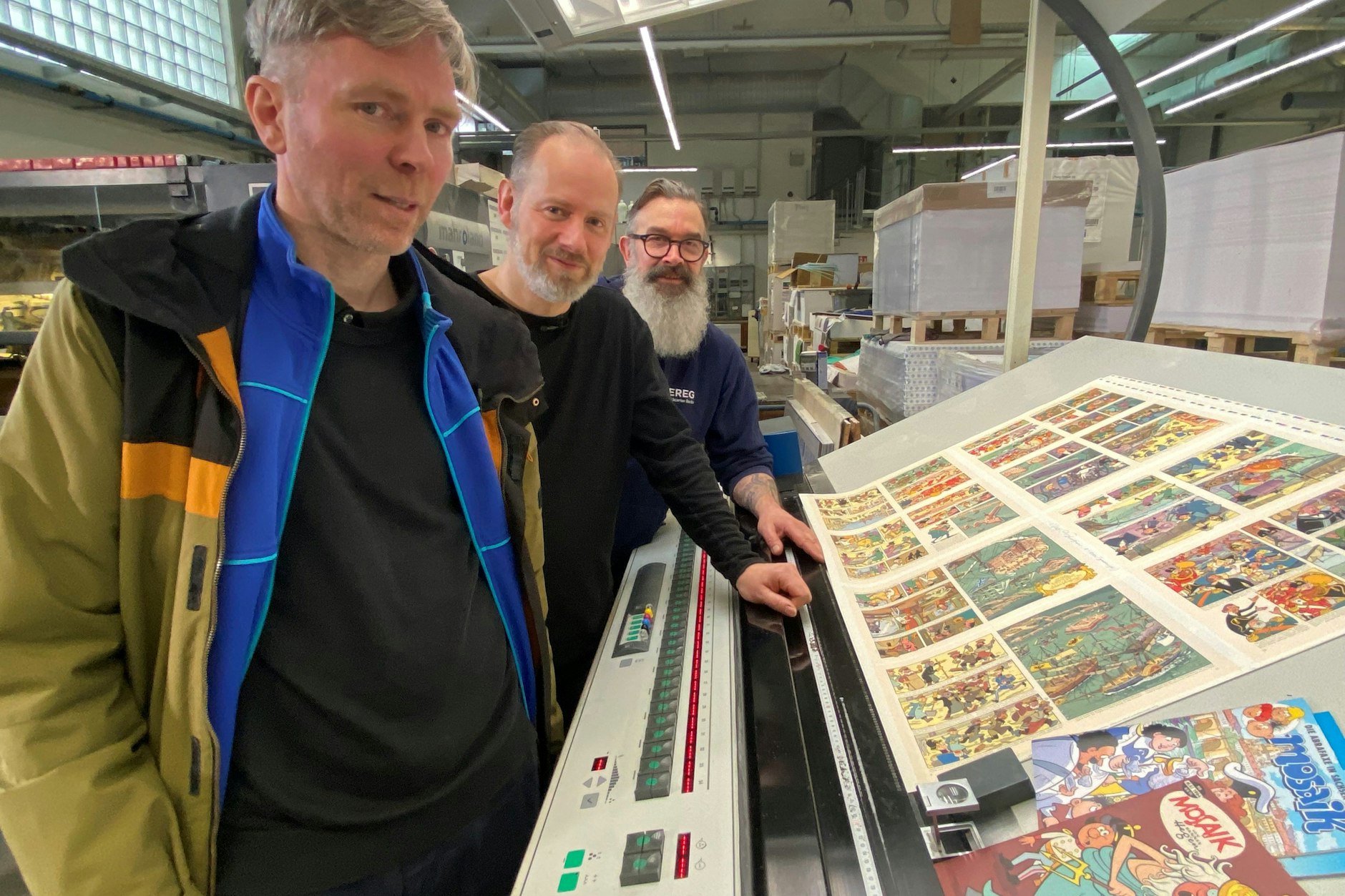Henning Krowiasch, Ulf S. Graupner und Drucker Henri Franz vor Druckstart am Kontrolltisch mit einem Testdruck.
