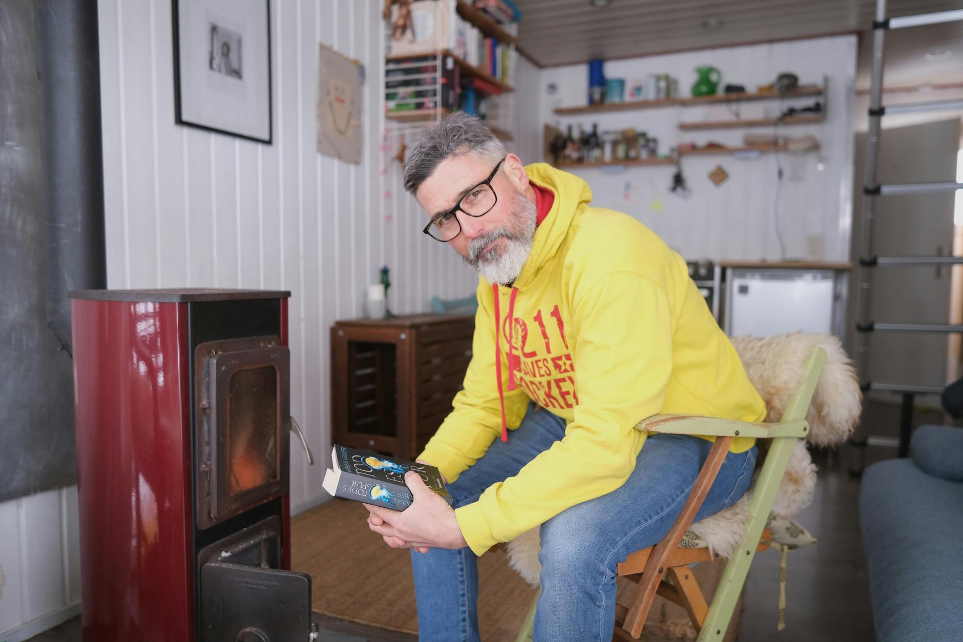 Christian P. Doetsch macht es sich an seinem Ofen mit einen Buch gemütlich.