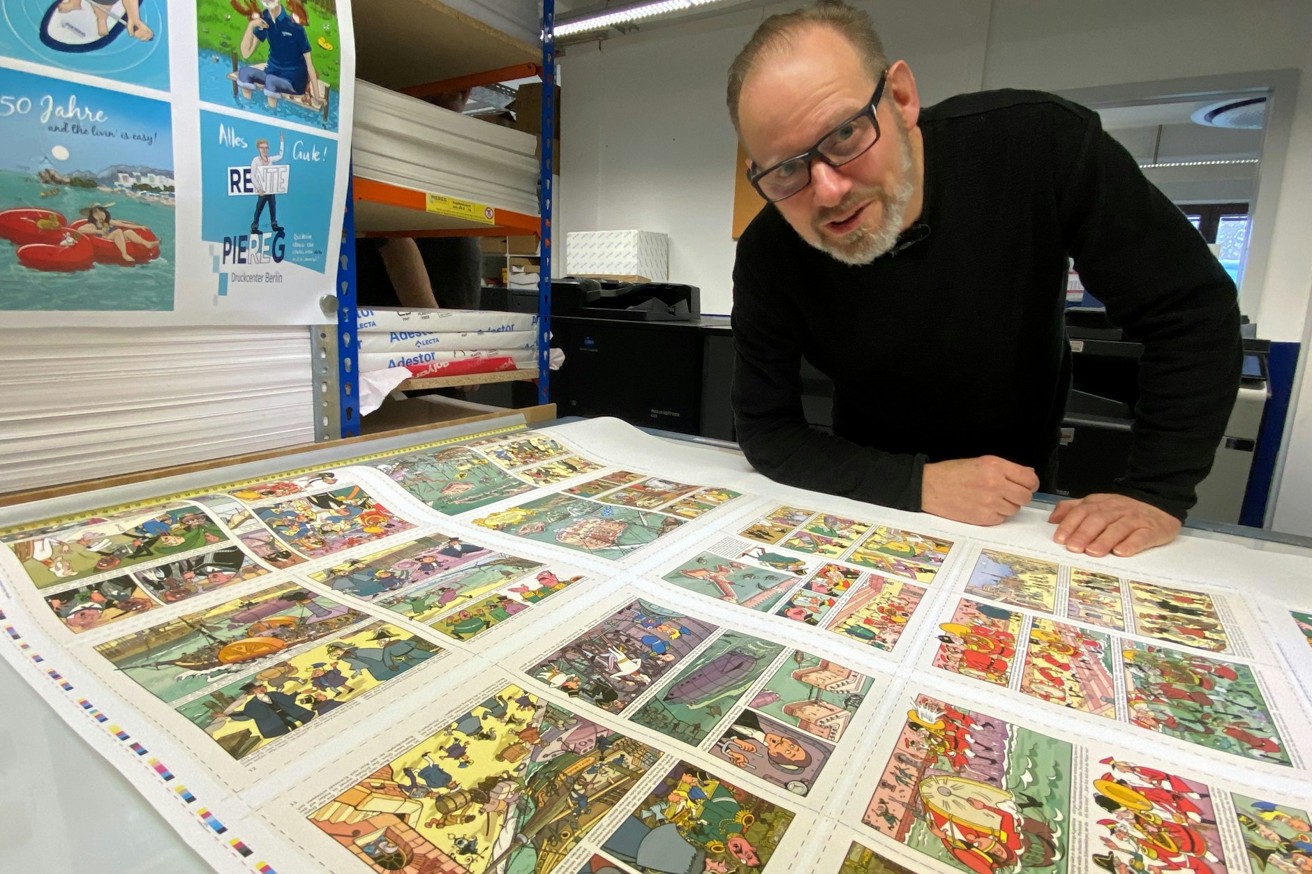 Zeichner Ulf S. Graubner begutachtet den Druckbogen mit den Seiten des Mosaik-Heftes.
