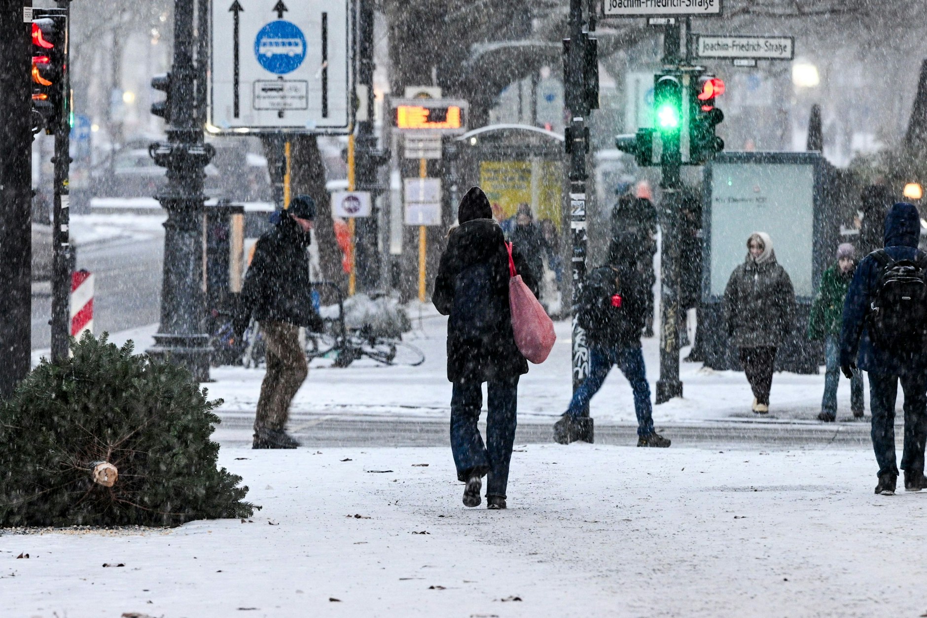 Passanten sind am späten Montagnachmittag bei einsetzendem Schneefall auf dem Kurfürstendamm unterwegs. In der Nacht zu Dienstag bildete sich Glatteis.