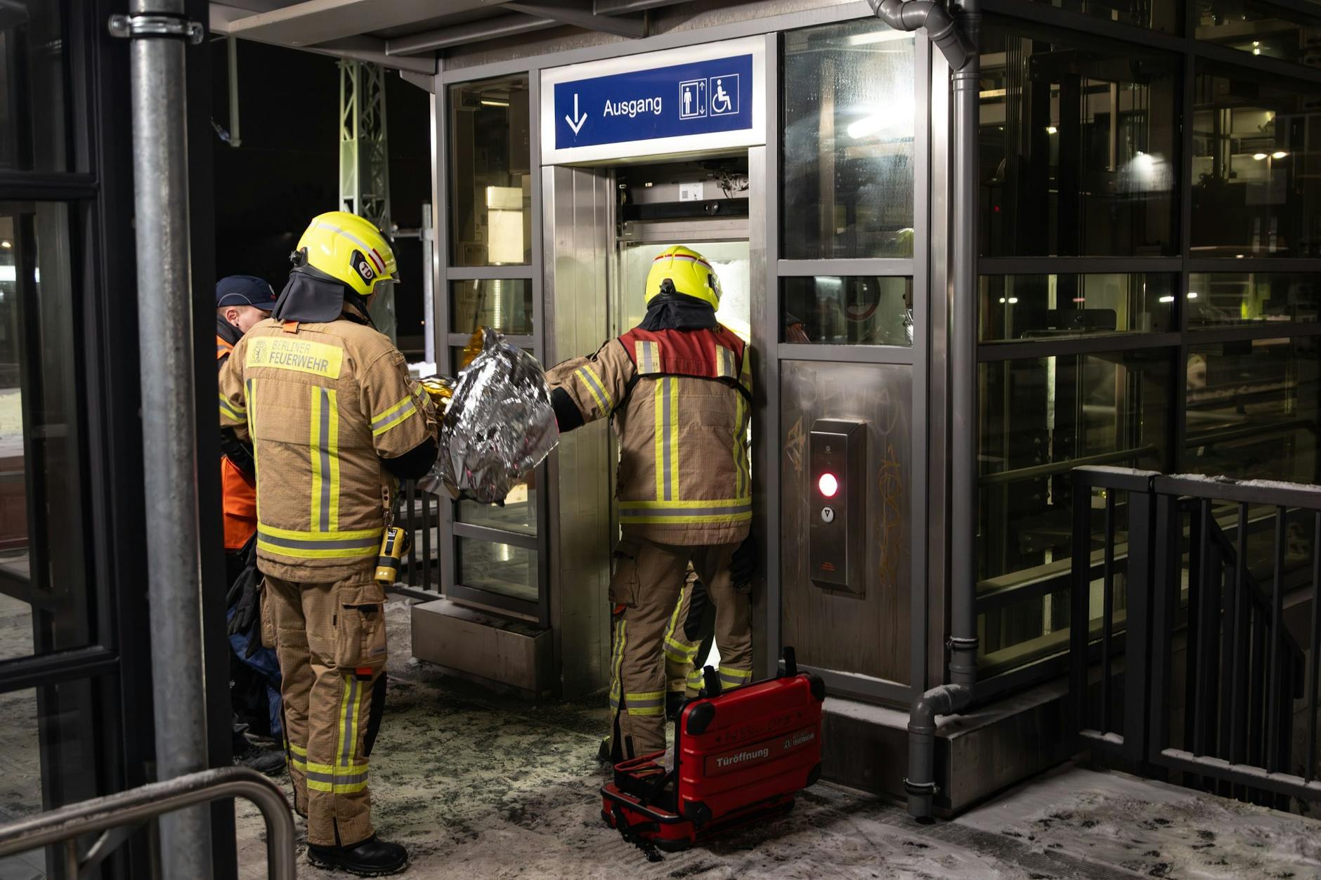 Feuerwehrleute reichen der Mutter und ihrem Kind eine Thermodecke, um sie im kalten Fahrstuhl vor dem Auskühlen zu schützen.