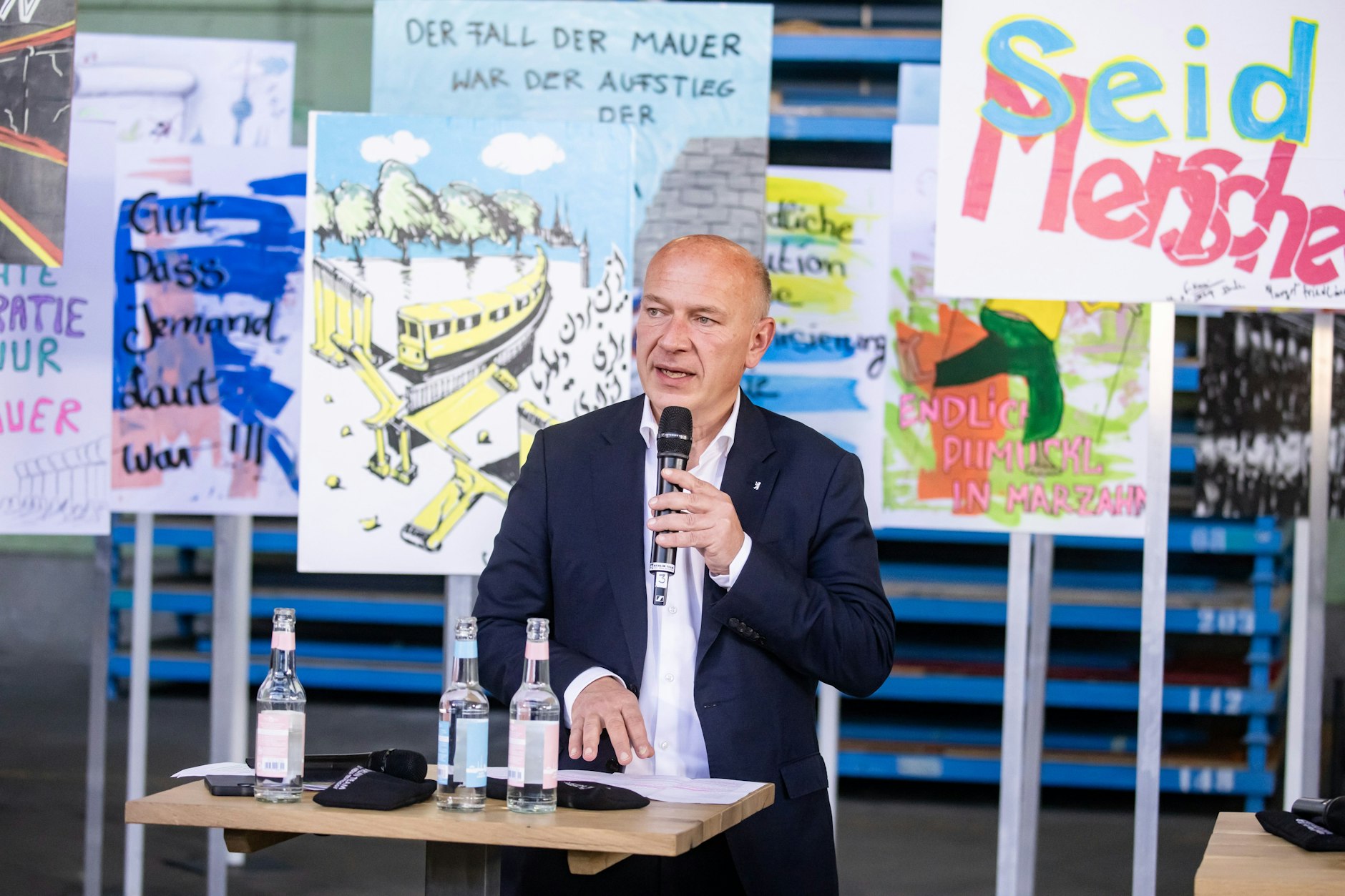 Bürgermeister Kai Wegner während der Feierlichkeiten zu „35 Jahren Mauerfall“ in Berlin. Im Hintergrund ein Plakat: Seid Menschen.