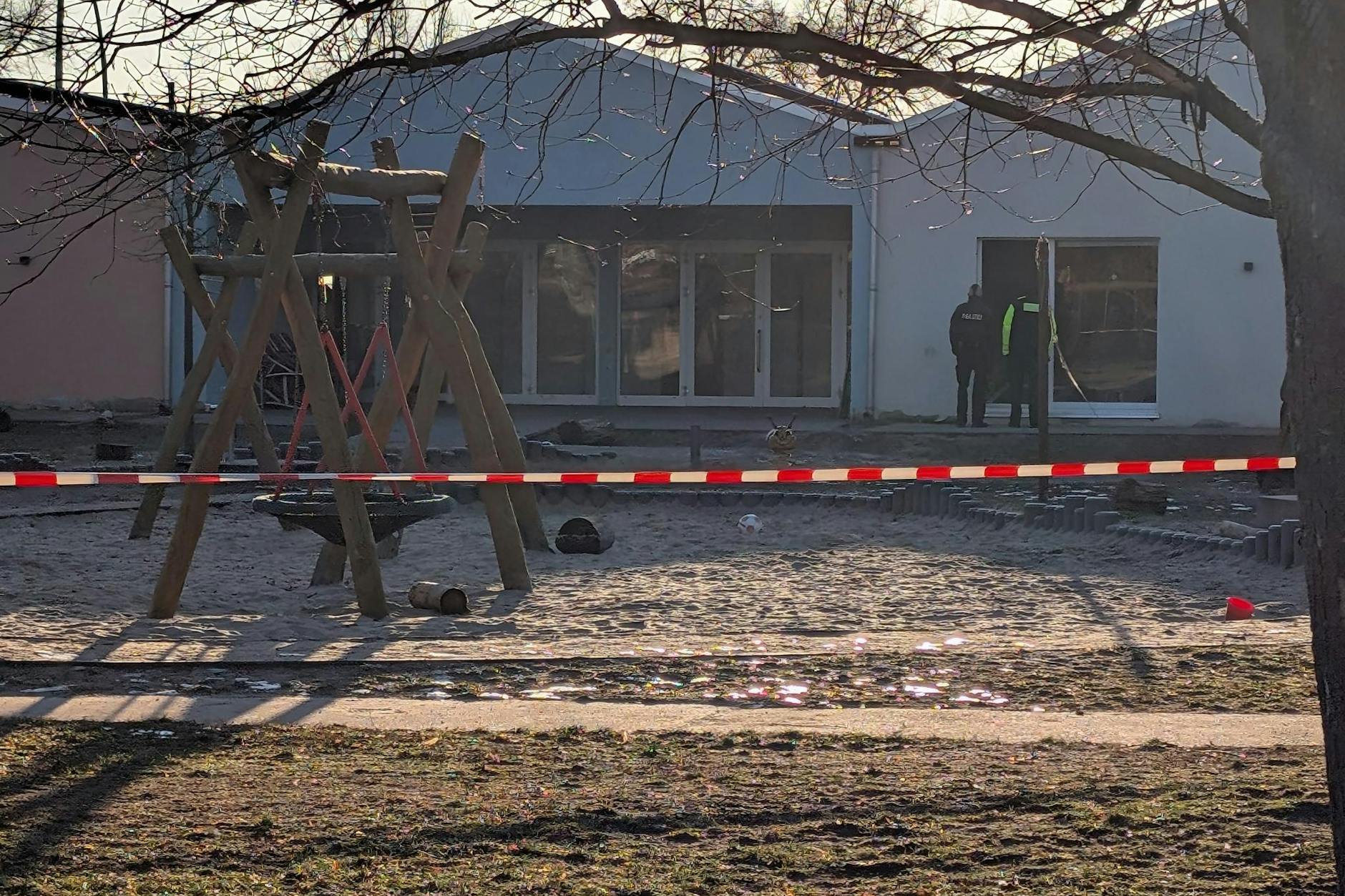 Einsatzkräfte der Berliner Polizei untersuchen den Eingangsbereich der Kita.