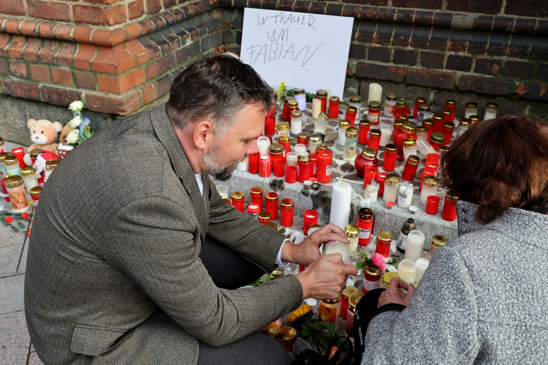 Jens-Peter Schulz (l.), Pastor der Ev.-Luth. Pfarrgemeinde Güstrow, entzündet mit einer Frau vor der Güstrower Marienkirche Kerzen, um an den kleinen Fabian zu erinnern.