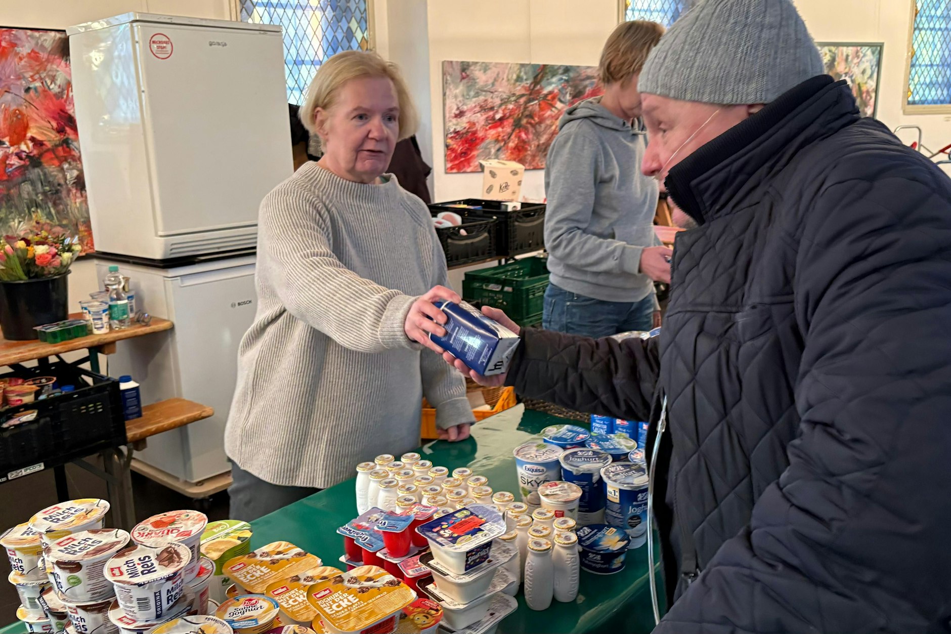 Helferin Susanna Hahn gibt ein Getränk an Krystian Musiol, der auf die Unterstützung angewiesen ist.