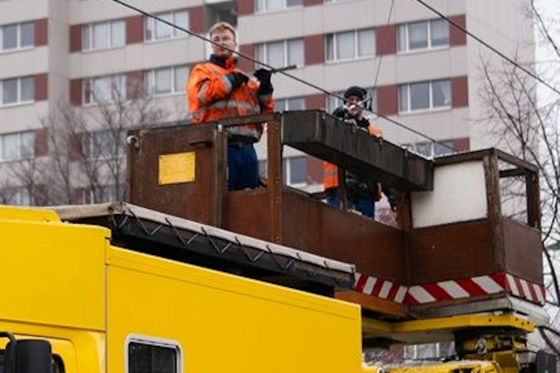 Eine der Besatzungen, die mit einem Turmwagen der BVG in Berlin die Straßenbahn-Oberleitungen enteisen.
