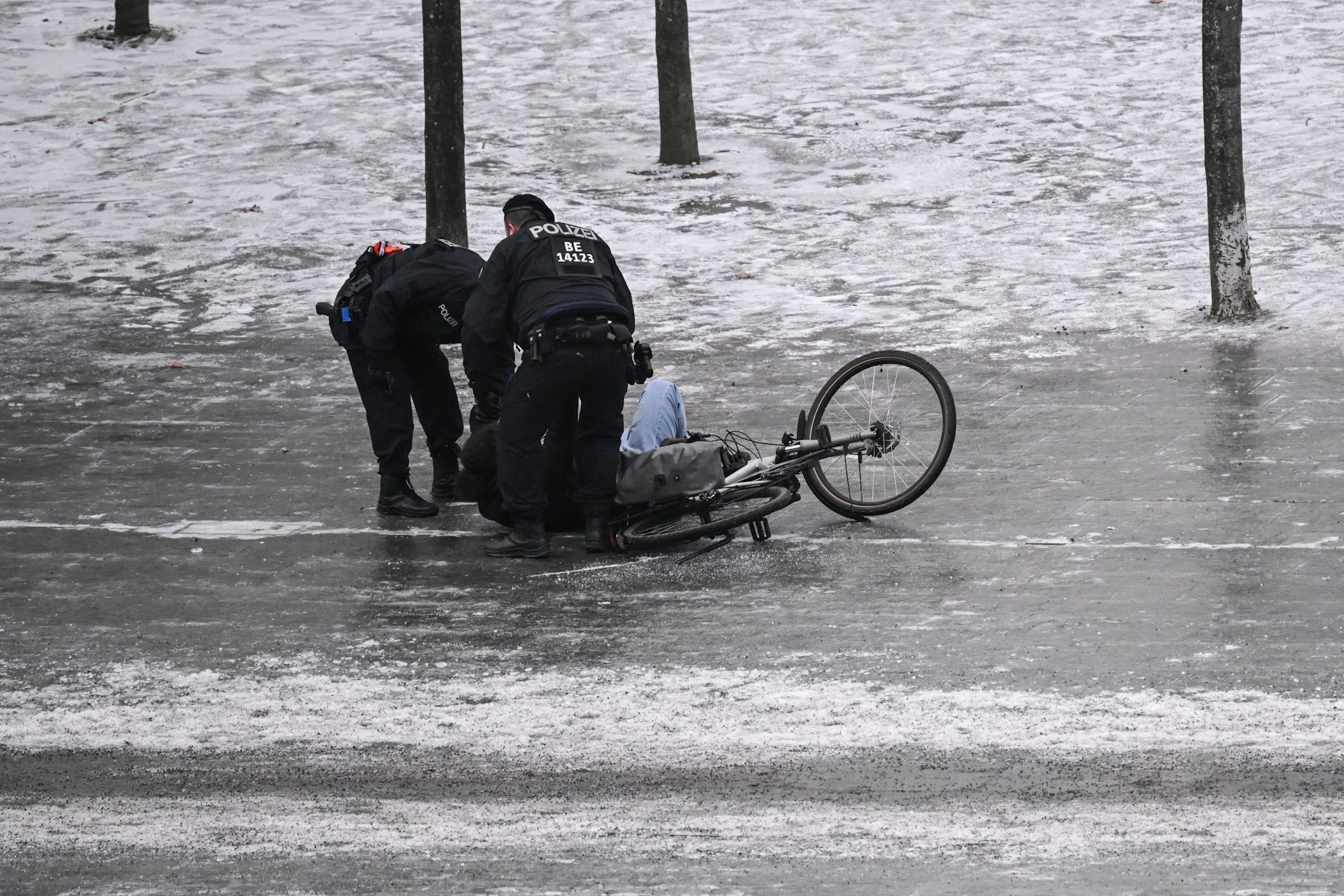 Polizisten helfen am Donnerstag einem Fahrradfahrer in Berlin, der bei Glatteis ausgerutscht ist.