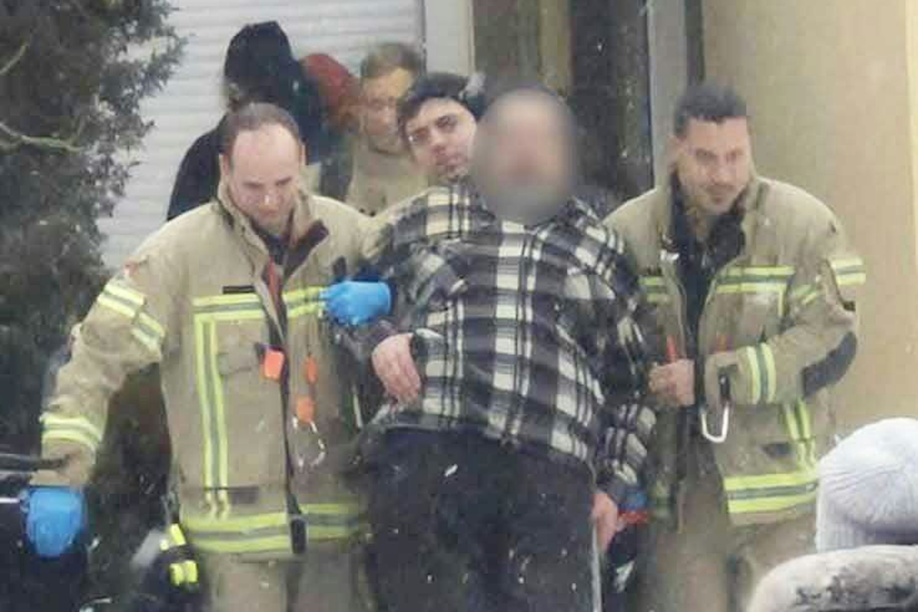 Feuerwehrleute transportieren einen Patienten mit einer Sackkarre zum Löschfahrzeug, um ihn ins Krankenhaus zu bringen.