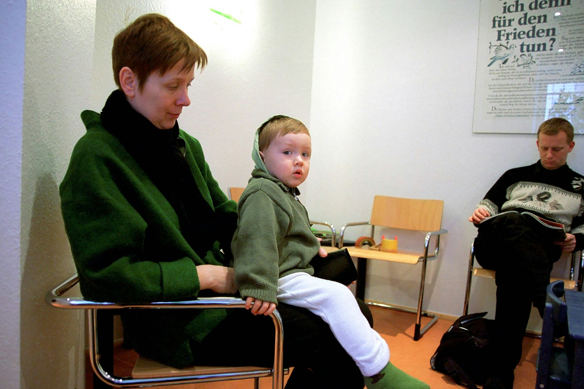 Eine Mutter sitzt mit ihrem Sohn im Wartezimmer einer Arztpraxis.