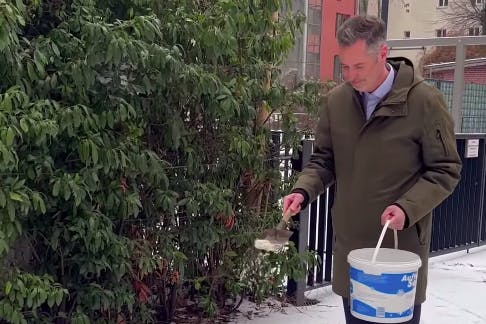 Christian Dürr greift selbst zum Streusalz und streut vor der FDP-Zentrale in Berlin-Mitte